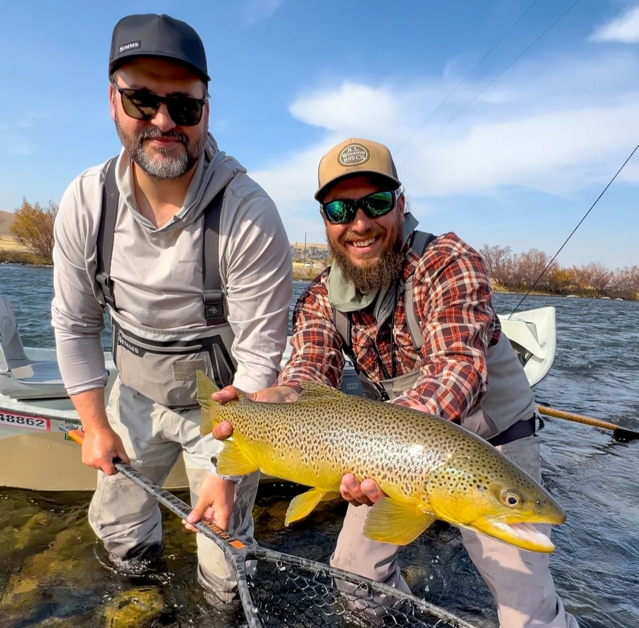 Guide holding a clients wild brown trout on the Madison River during a guided fly fishing trip with Rising Trout Fly Fishing Outfitters in Bozeman, Montana.
