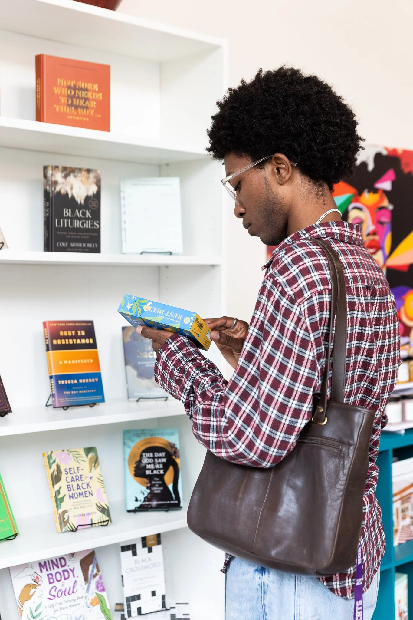 A Black person browsing the book selection at Zora's Place
