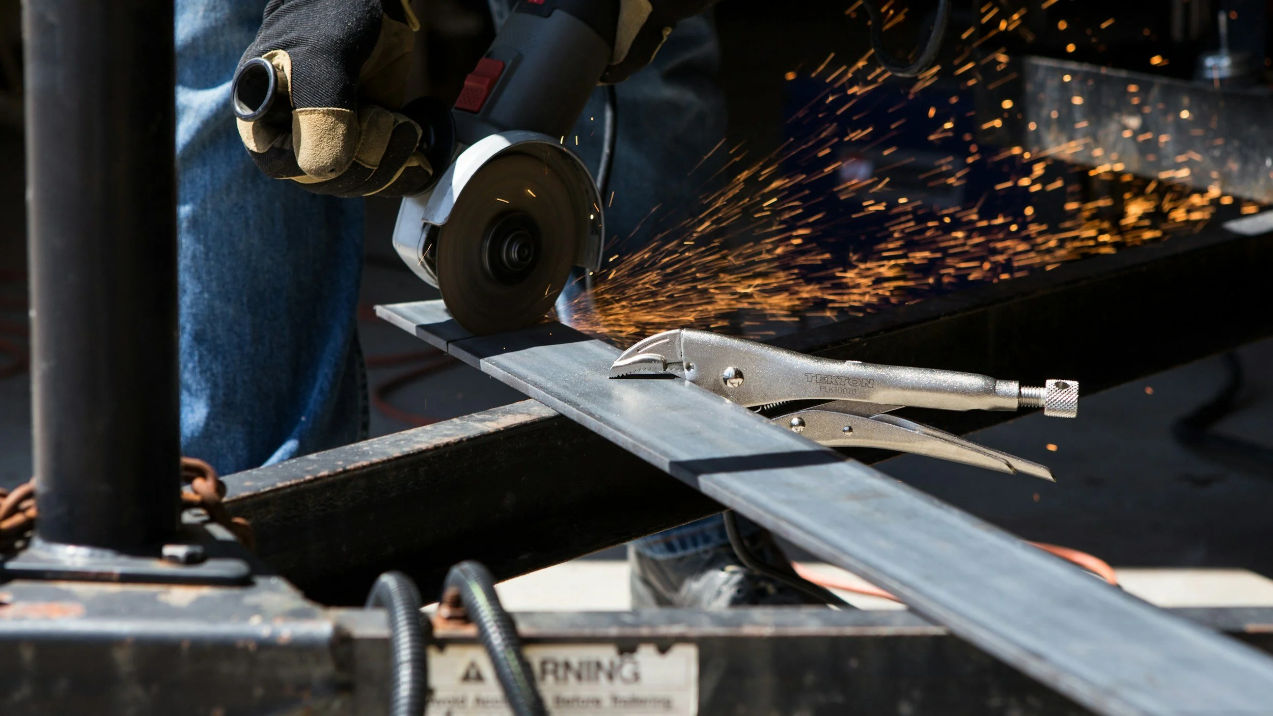 Angle grinder in action, cutting through metal sheet. man wearing safety gloves and goggles.