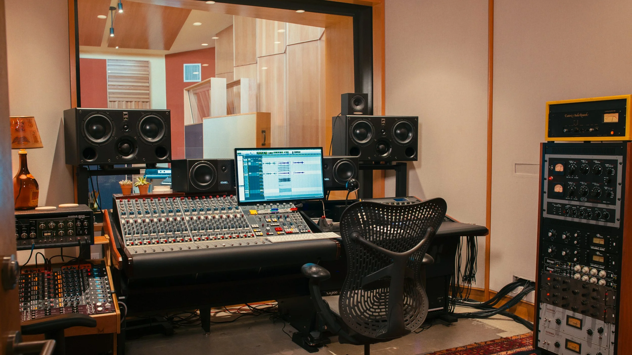 Recording studio with audio mixing console, speakers, computer monitor, and professional audio equipment.