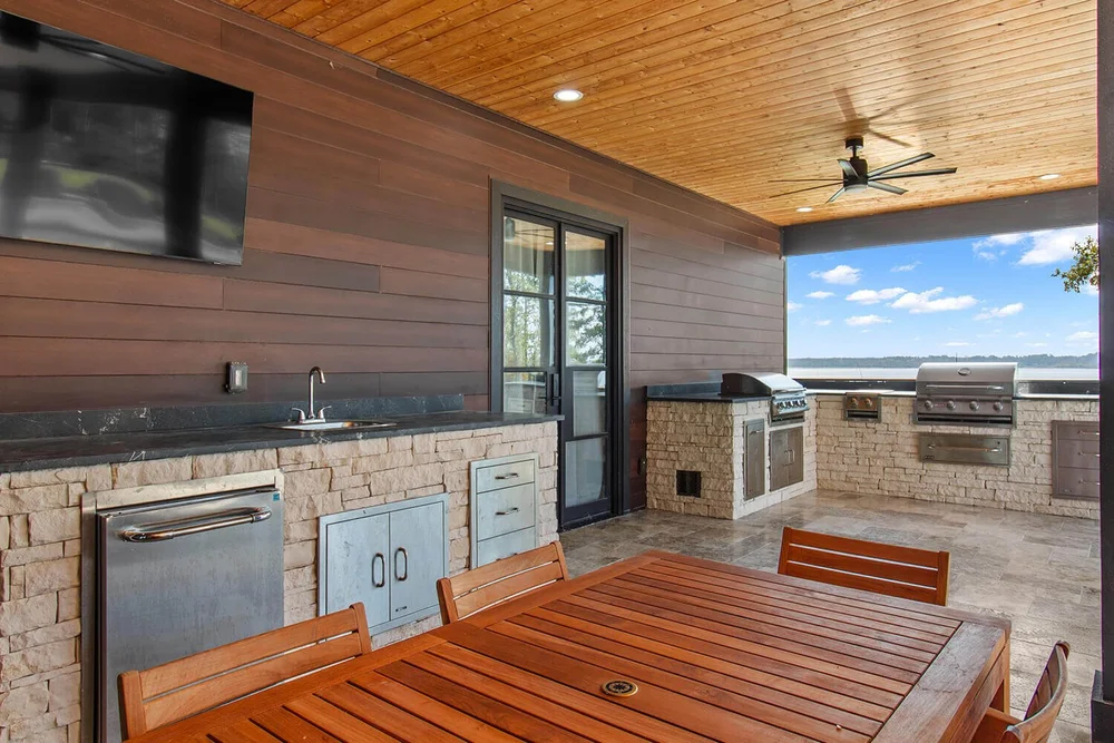Outdoor kitchen with built-in grill overlooking a lake — Aqua Logistics Custom Pools