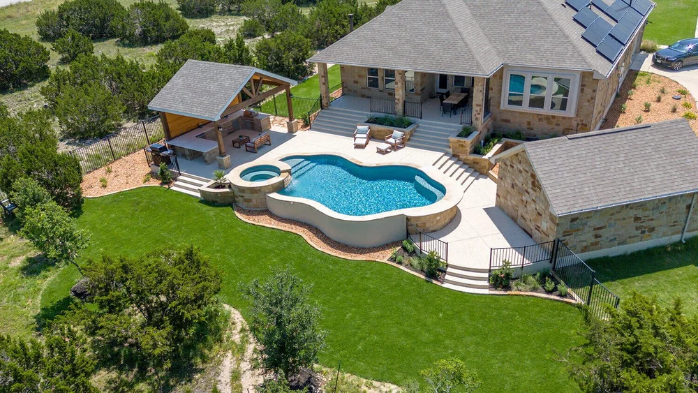 Aerial view kidney pool with hot tub and covered patio