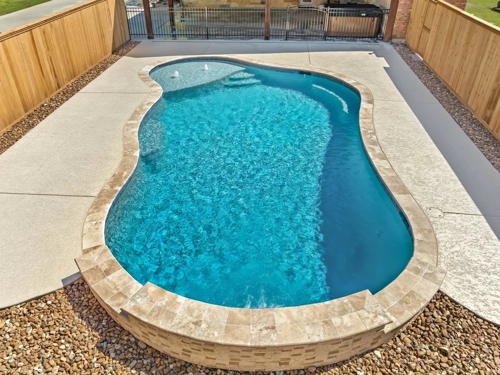 Kidney pool with stone tiles — Austin pool builder