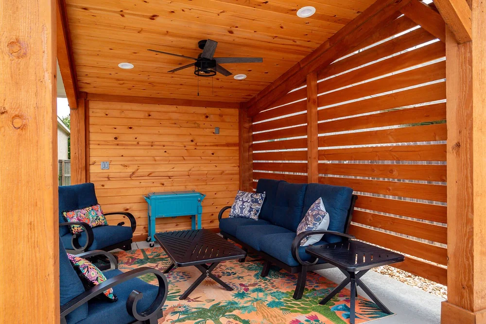 Covered outdoor patio with colorful cushions and ceiling fan