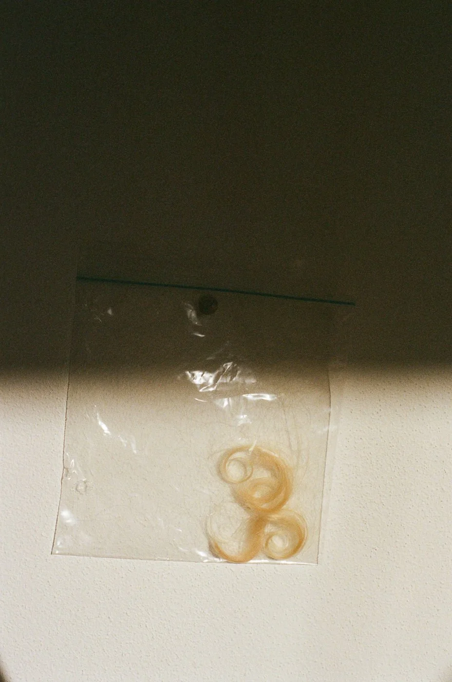 Abgeschnittene goldene Lockensträhne auf Tisch – symbolische Familienaufnahme