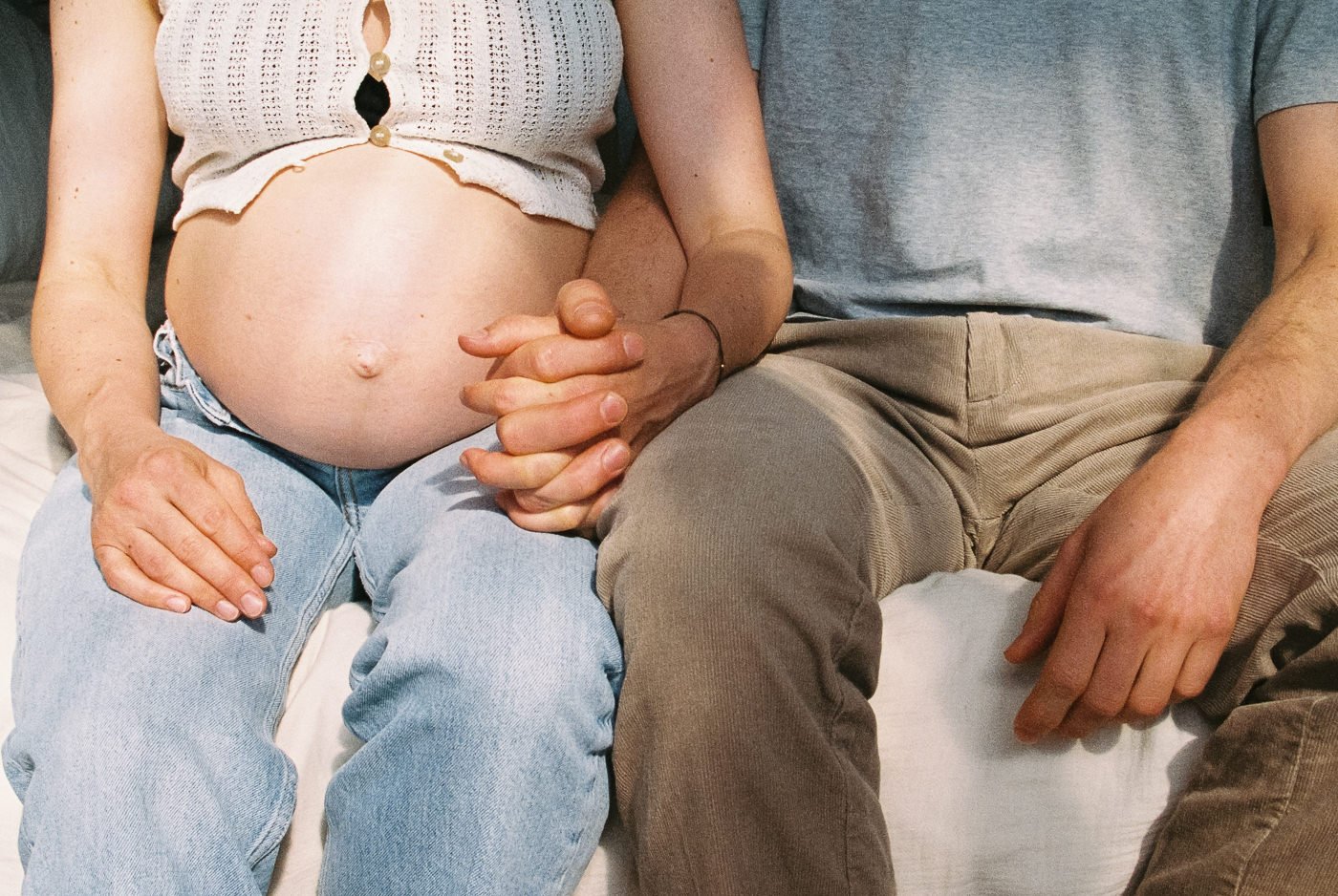 Paar hält Hände über Babybauch bei Schwangerschaftsfotografie in Mainz