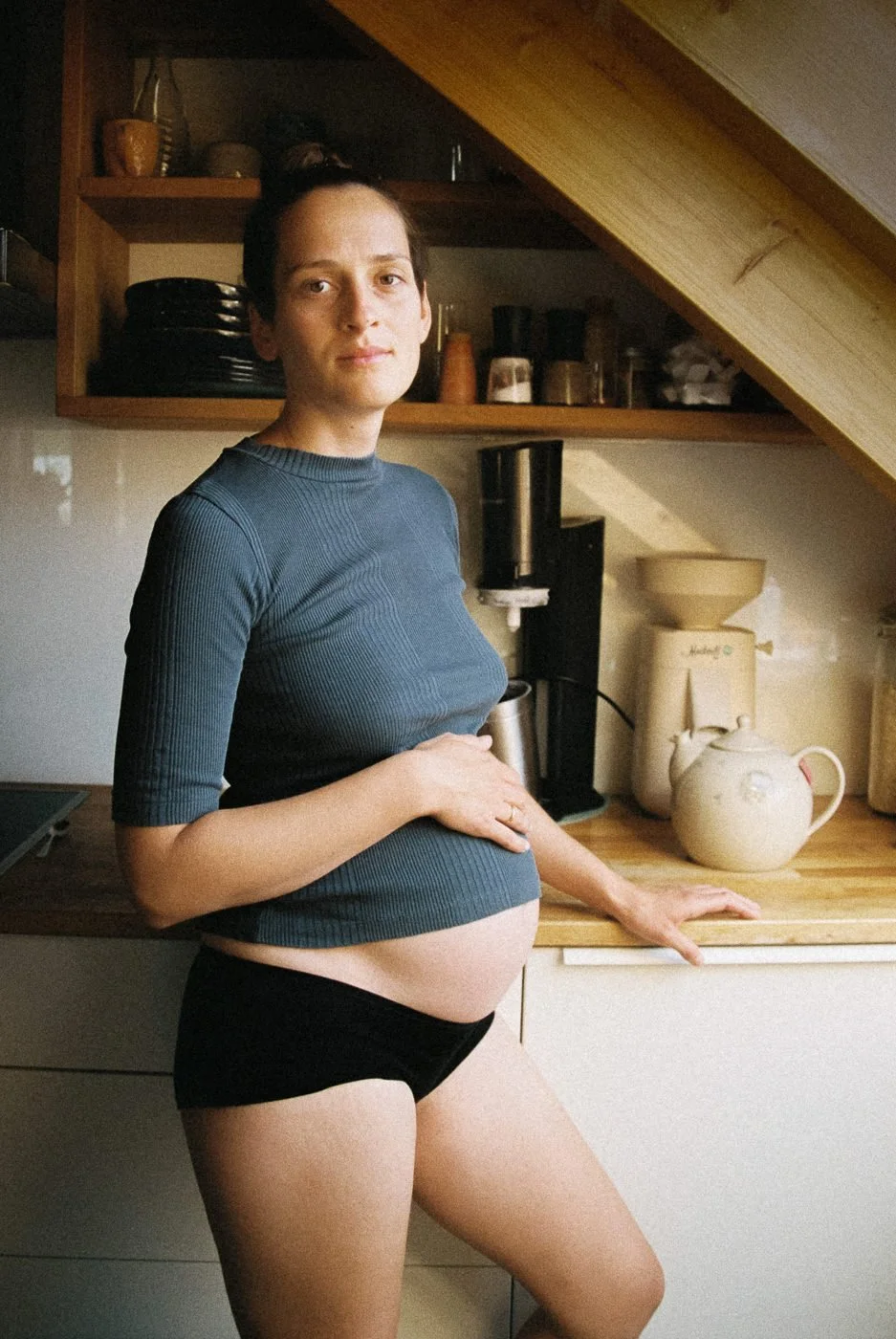 Schwangere Frau steht in der Küche und hält ihren Babybauch – Schwangerschaftsfotografie in Mainz