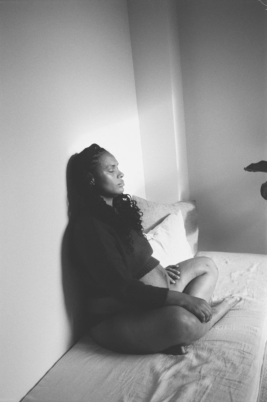 Schwangere Frau sitzt zu Hause auf dem Sofa – analoges Schwarz-Weiß Familien- und Schwangerschaftsportrait in Mainz