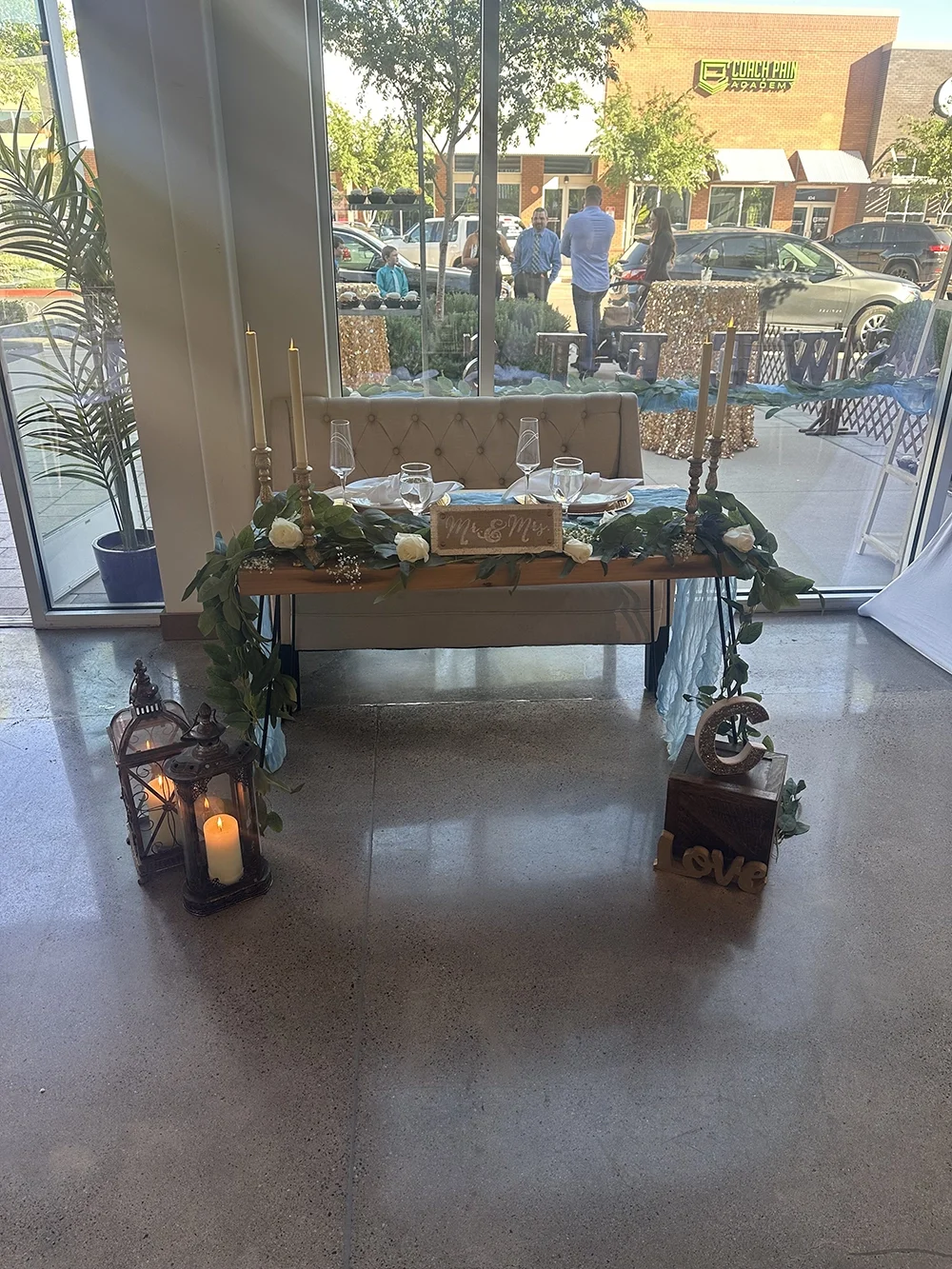 Wedding reception table setup with candles, greenery, and a 
