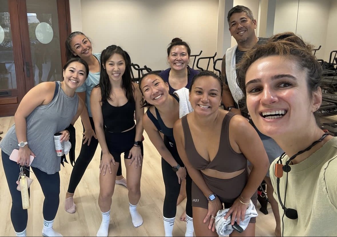 Group of people in workout attire smiling indoors.