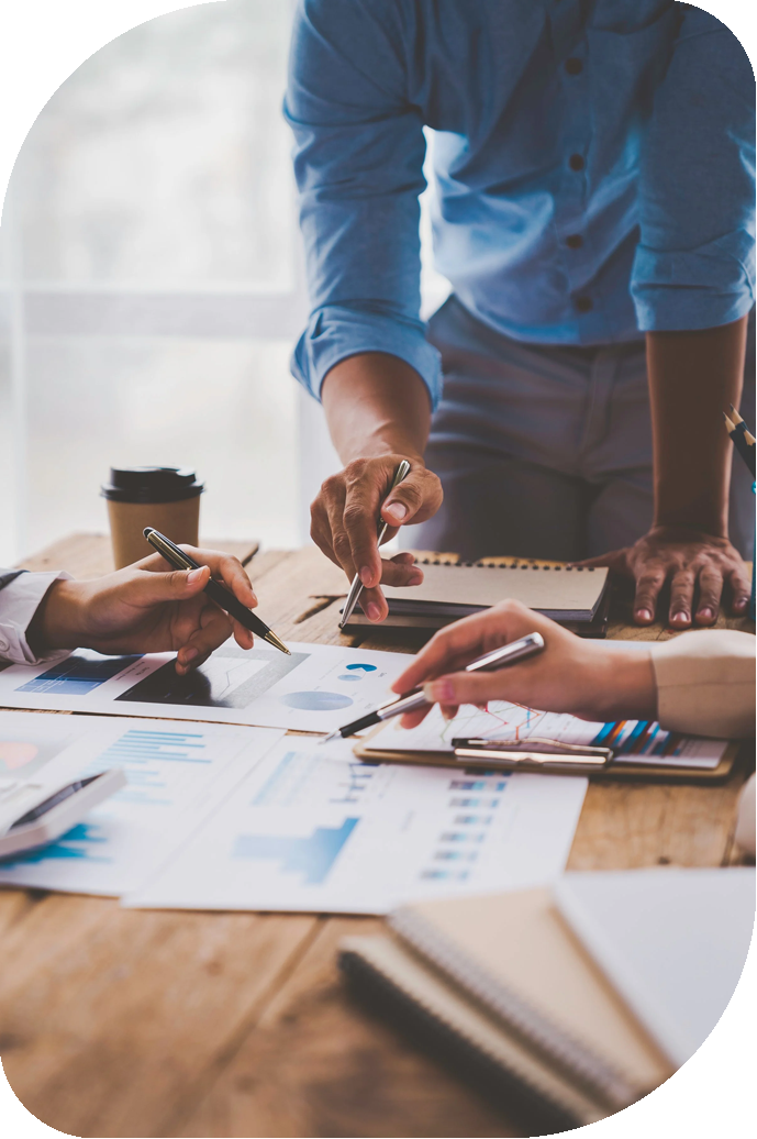 Business people reviewing financial charts and graphs on paper and tablets during a meeting.