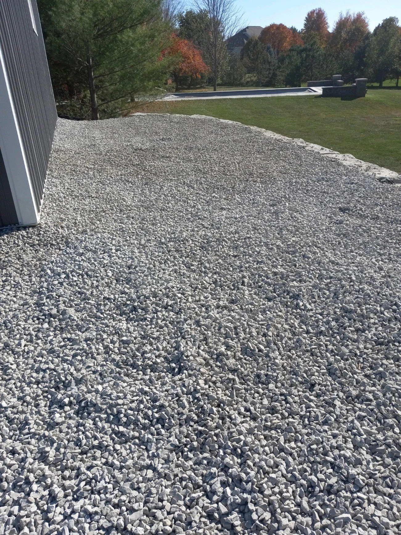Gravel-covered area beside a building with trees in the background