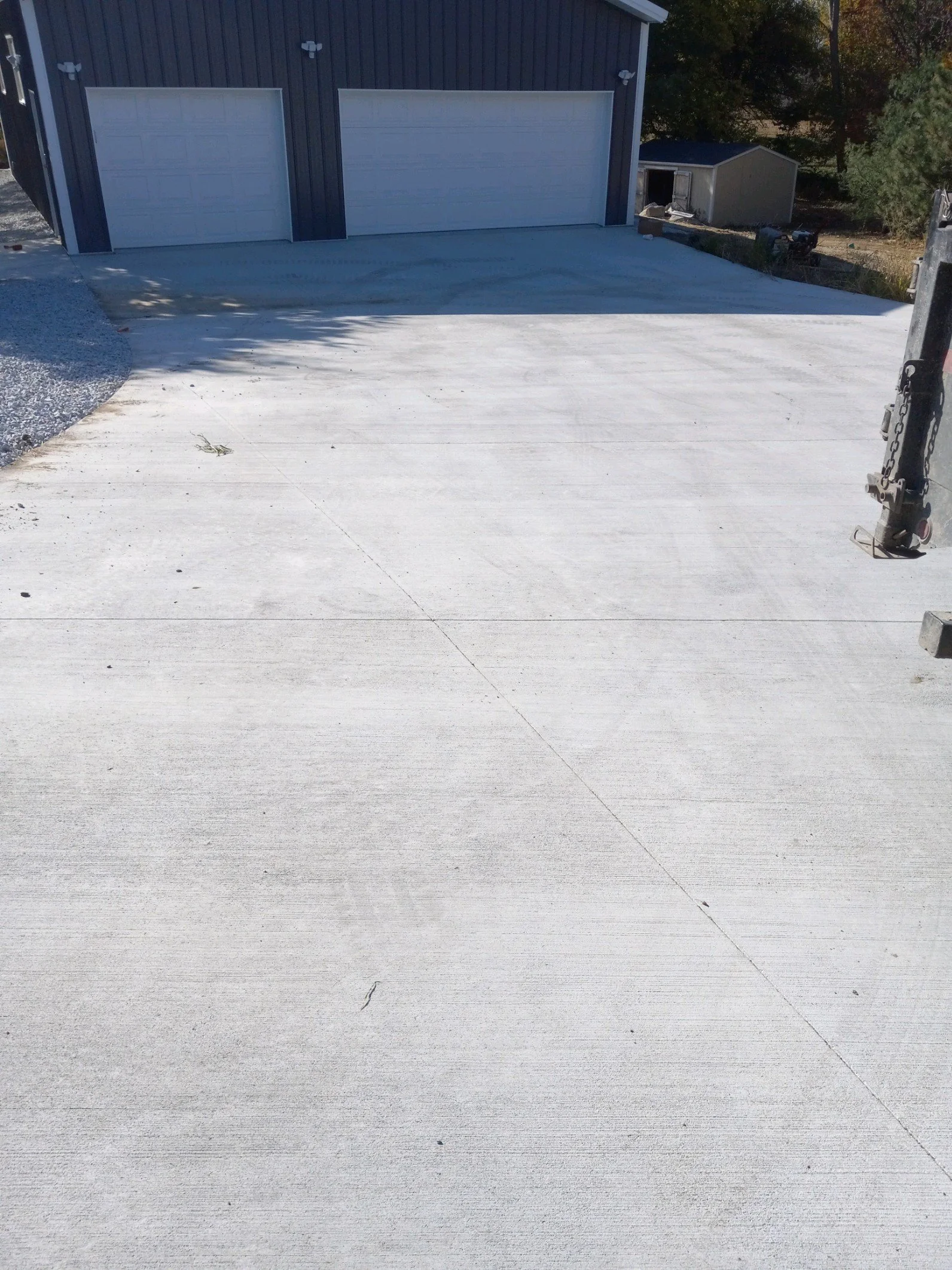 Concrete driveway leading to a garage with two white doors.