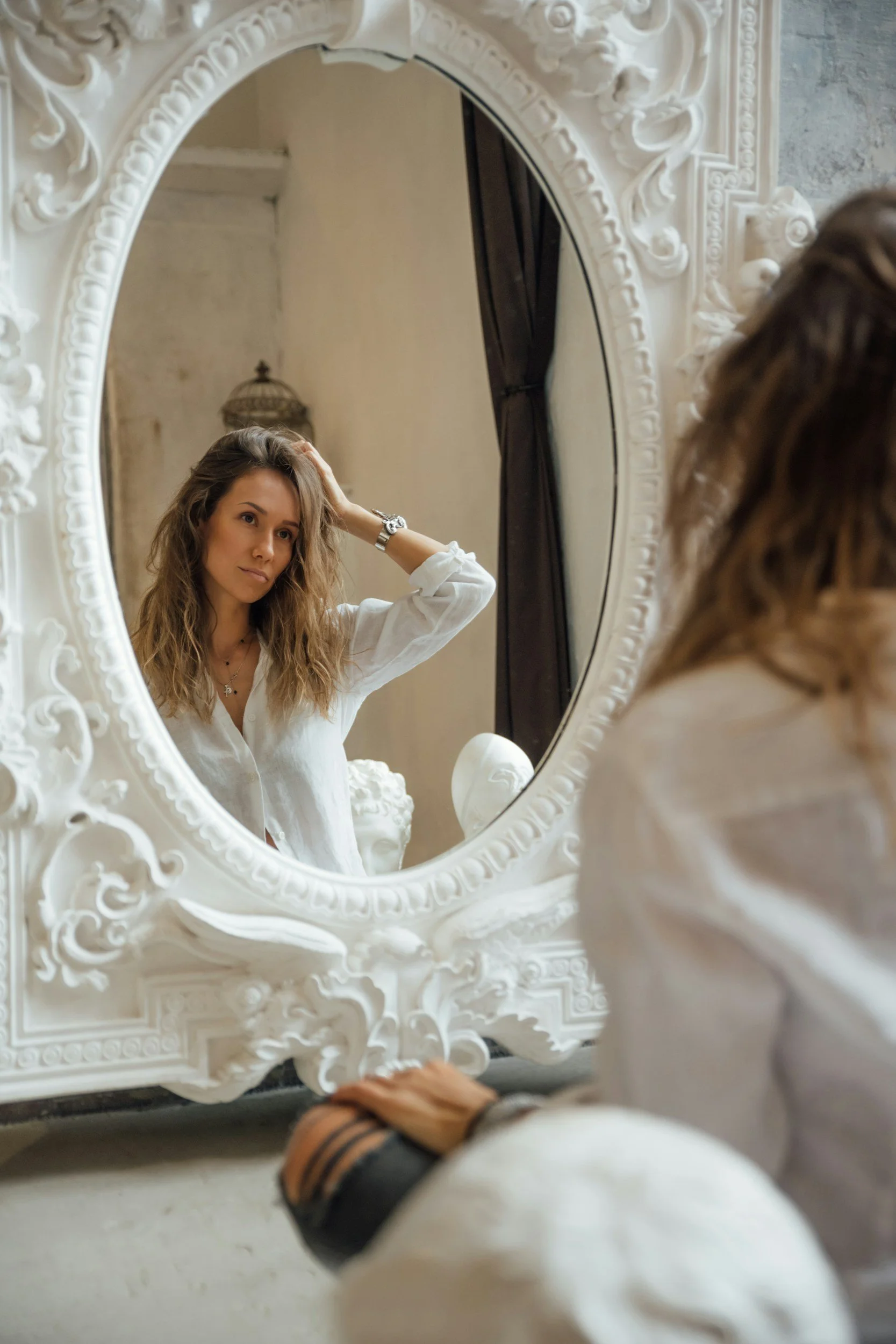 A person looking at their reflection in an ornate mirror.