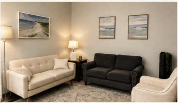 Living room with beige and black sofas, a wooden side table, two lamps, framed landscape art, and a patterned rug.