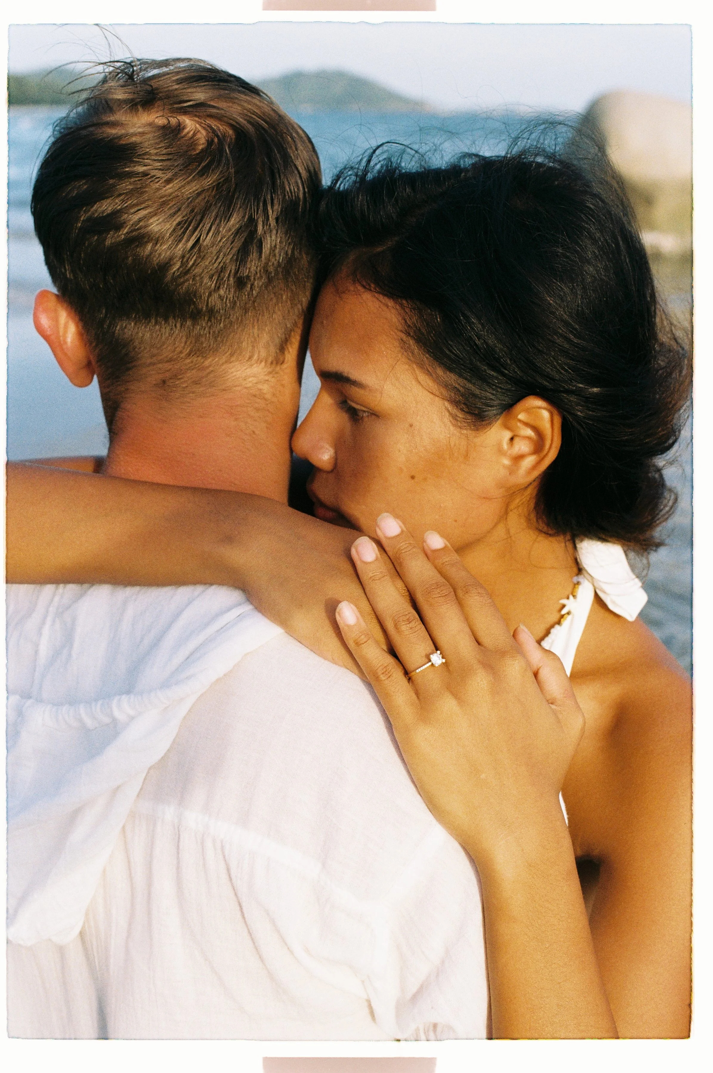 A couple embracing, with the woman showing an engagement ring on her finger.