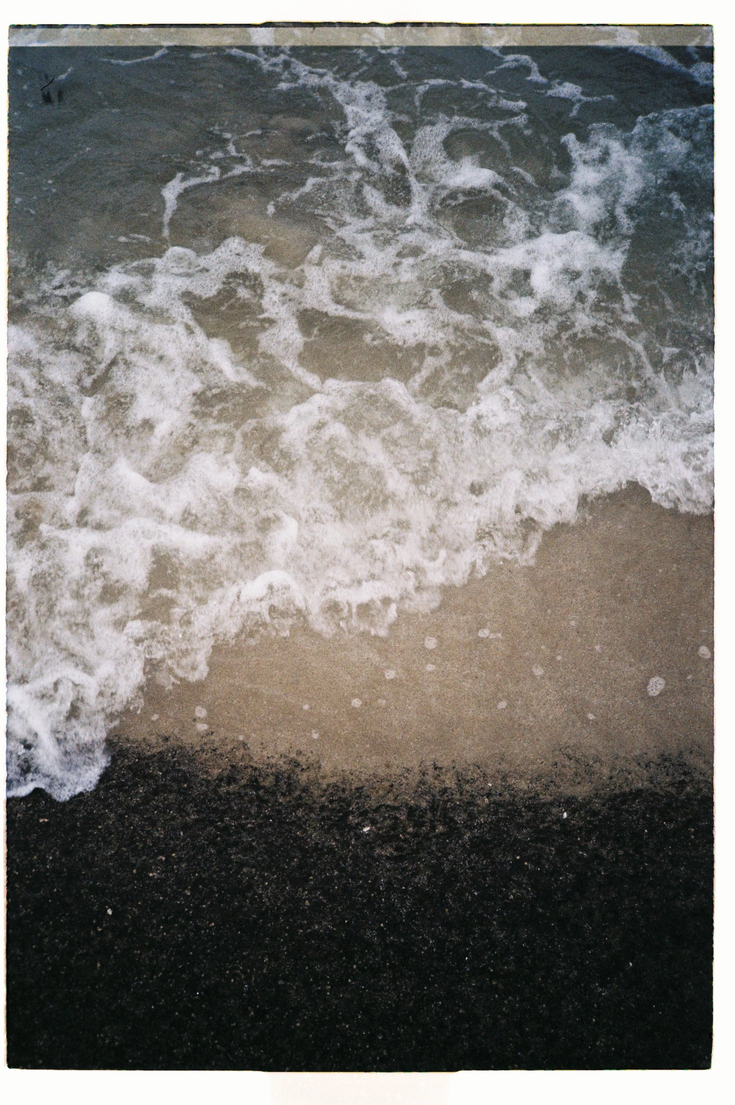 Waves crashing onto a sandy beach, with dark wet sand in the foreground.