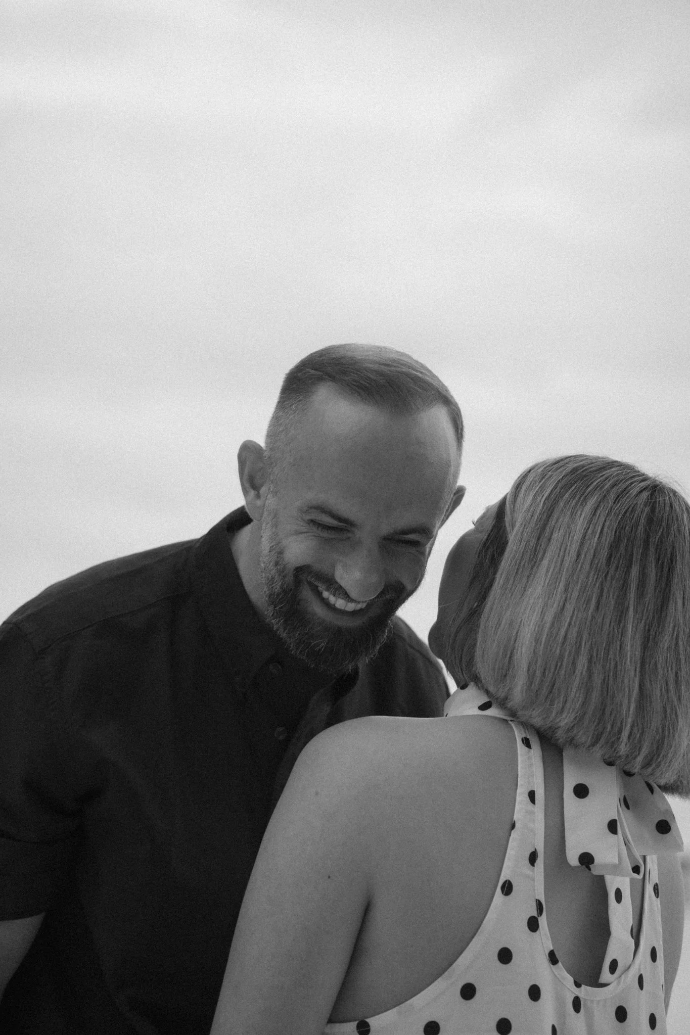 A man and woman sharing a kiss, with the man smiling.