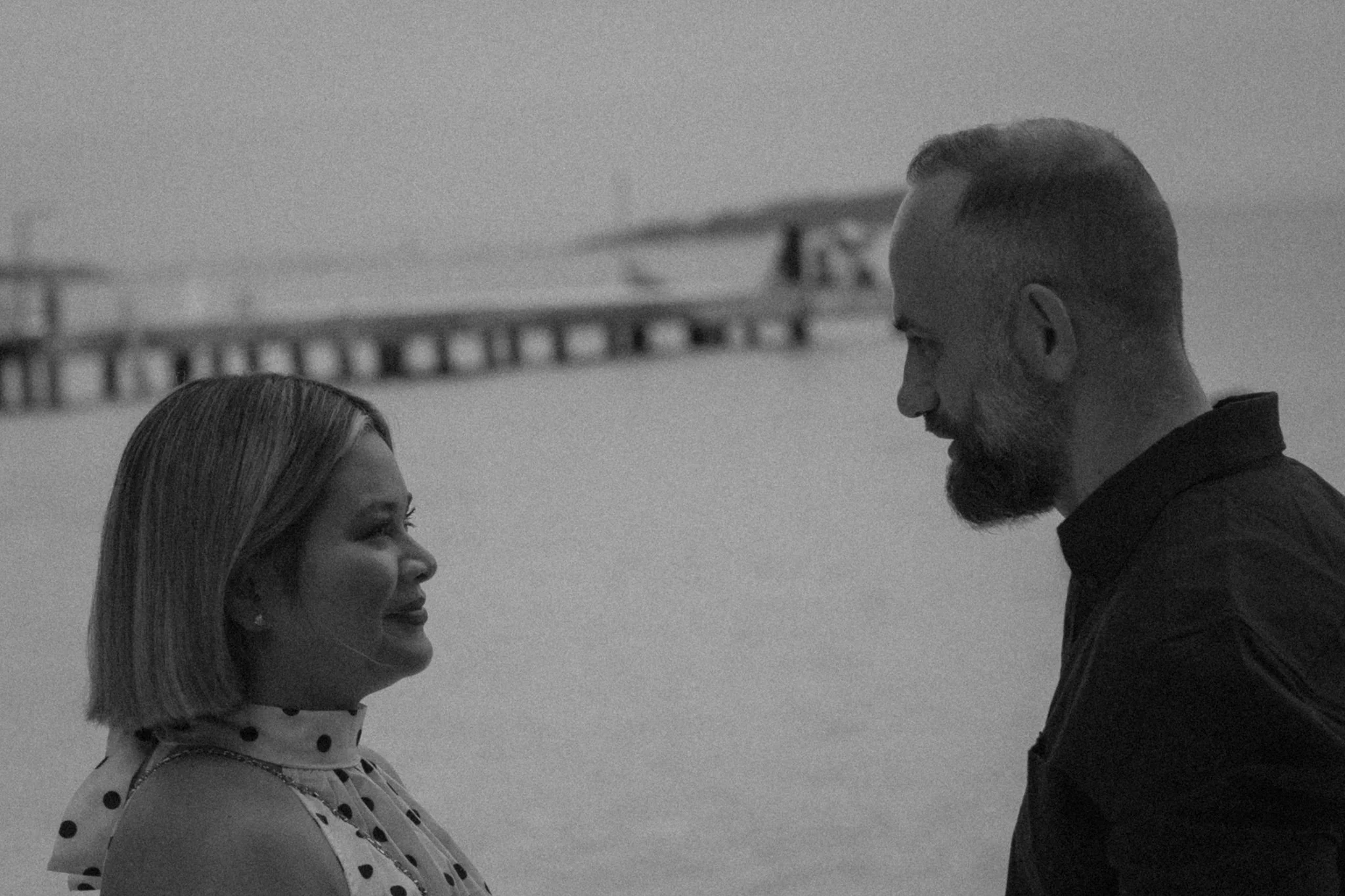 A black and white photo of a man and a woman standing close and facing each other.