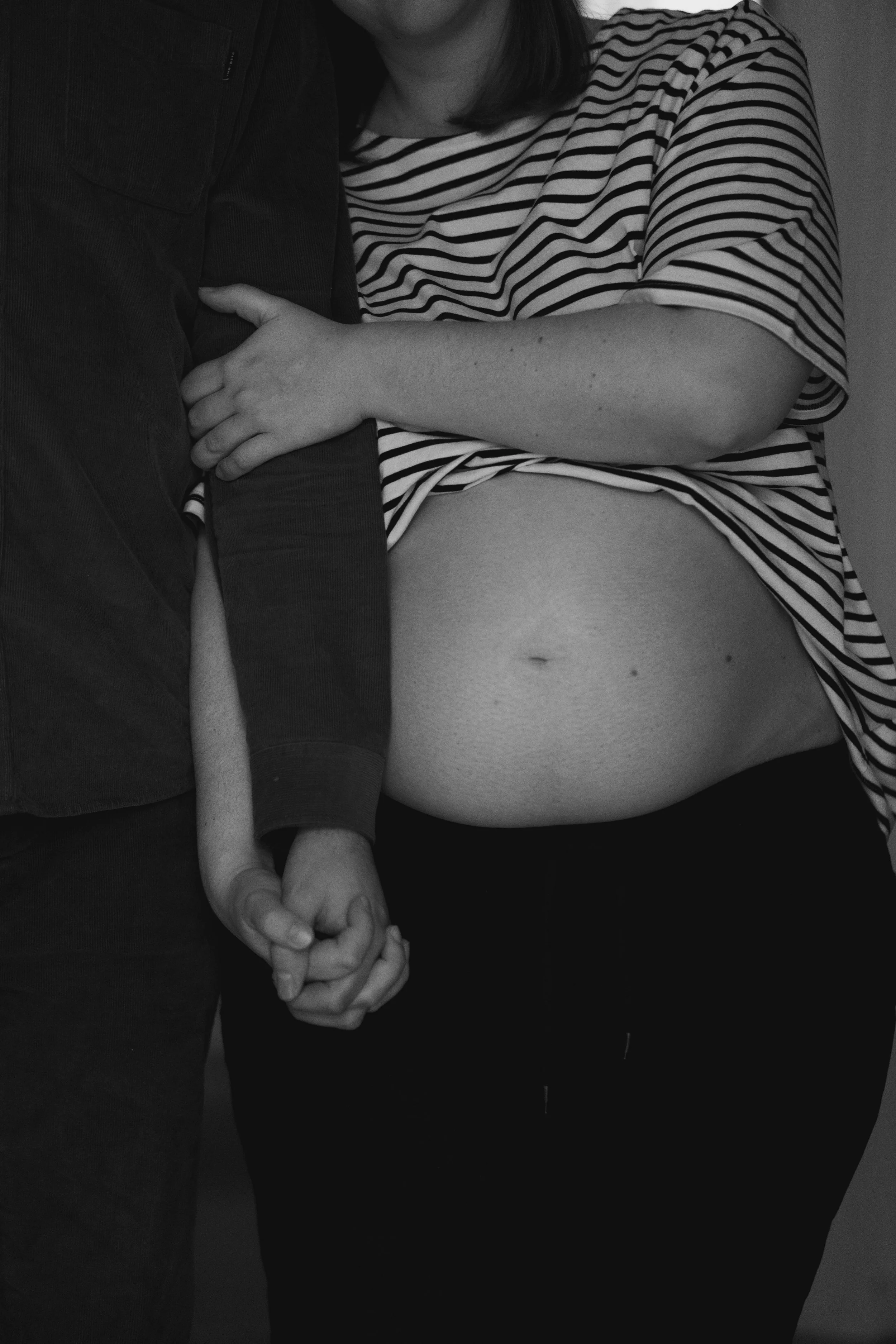 The image shows two people holding hands, one person is wearing a striped shirt and the other a dark-colored jacket.