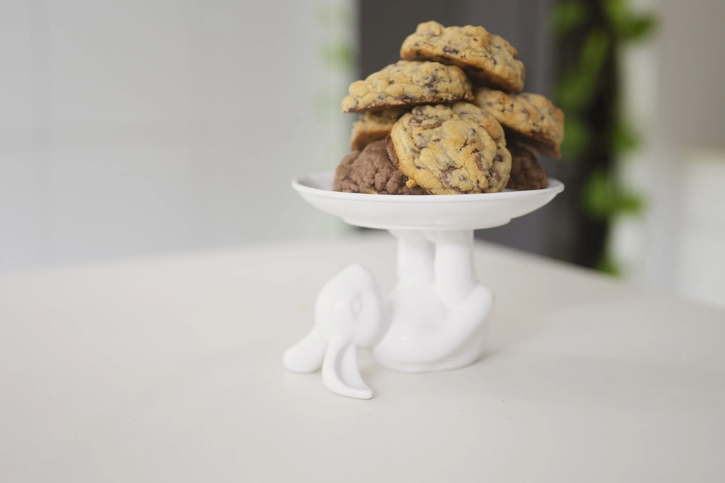 Stack of chocolate chip cookies and chocolate cookies on a white elephant-shaped serving stand.