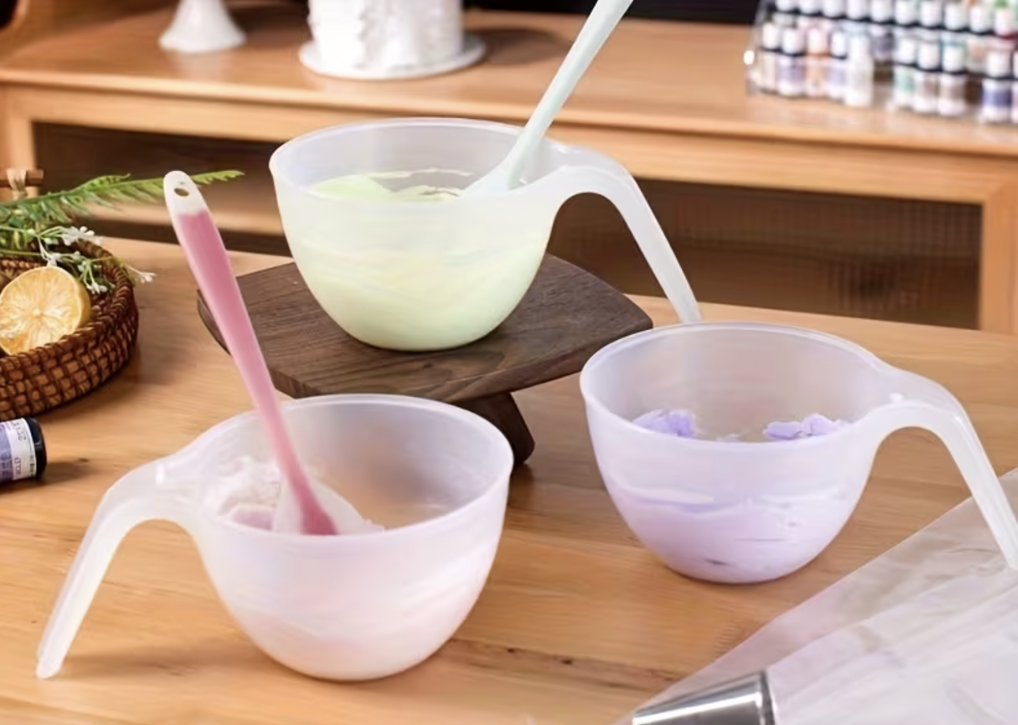 Three star-shaped plastic bowls with flat handles and pastel-colored spoons, filled with flavored ice or shaved ice, arranged on a wooden table. The bowls are in white, pink, and purple colors.