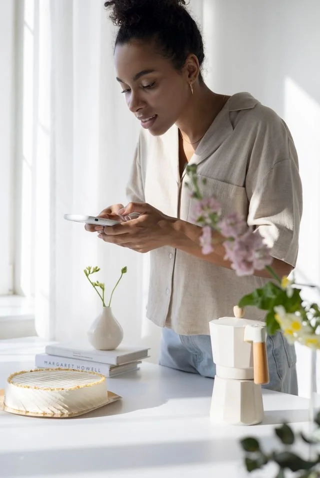 Woman holding a phone with a cake and other props on a table