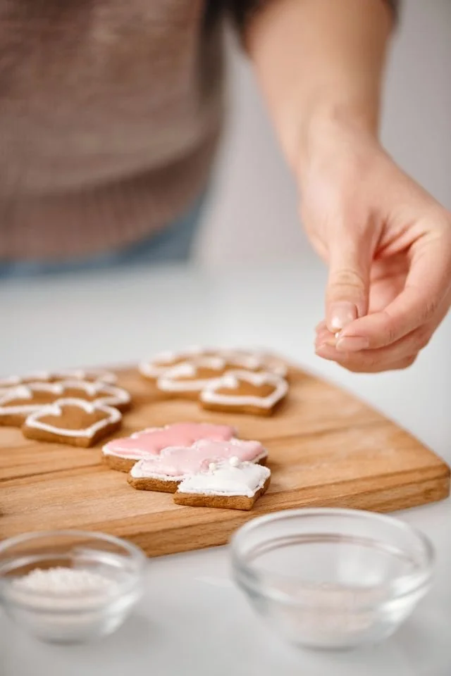 Hand decorating royal icing cookie on a timber board