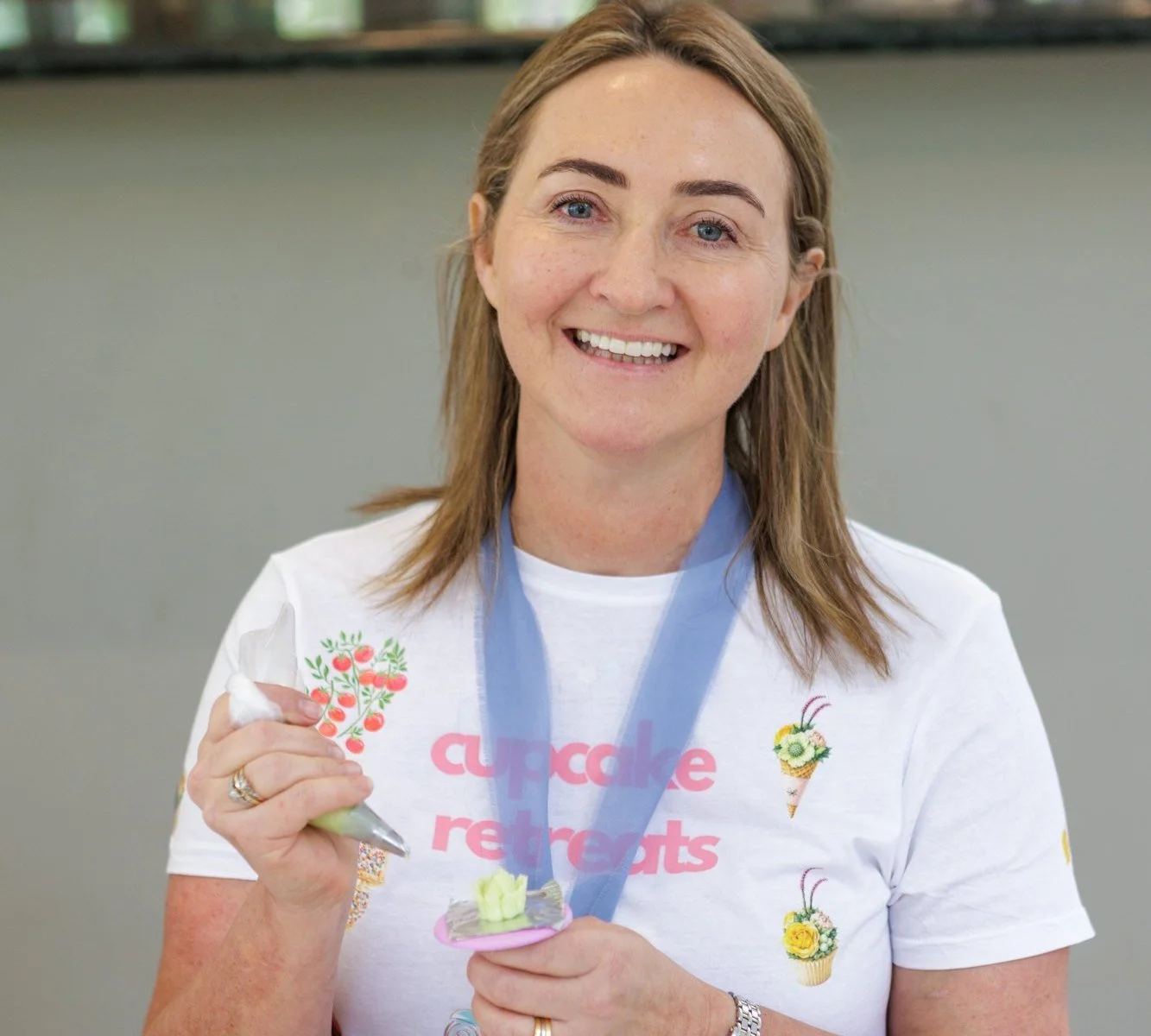 Melissa smiling with the buttercream flower she piped at the 2026 Cupcake Retreat