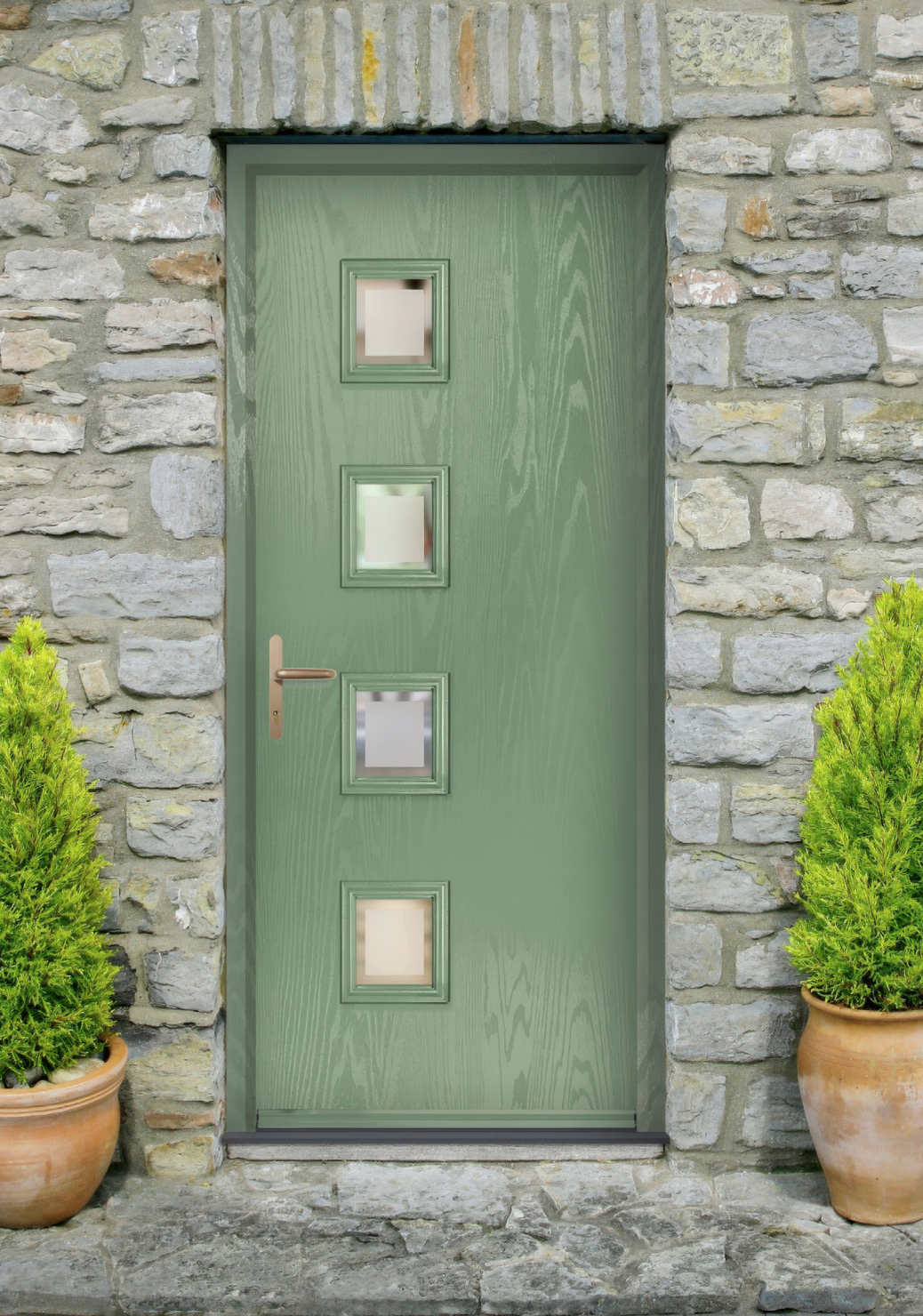 A green wooden door with four square windows, set in a stone wall, flanked by two potted green shrubs.