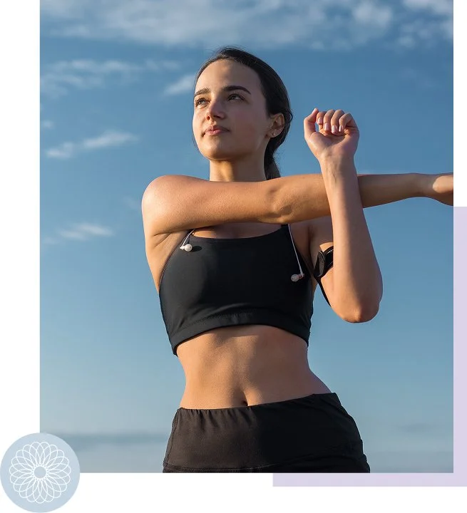 Young woman stretching outdoors against a blue sky with a few clouds, wearing black athletic clothing.