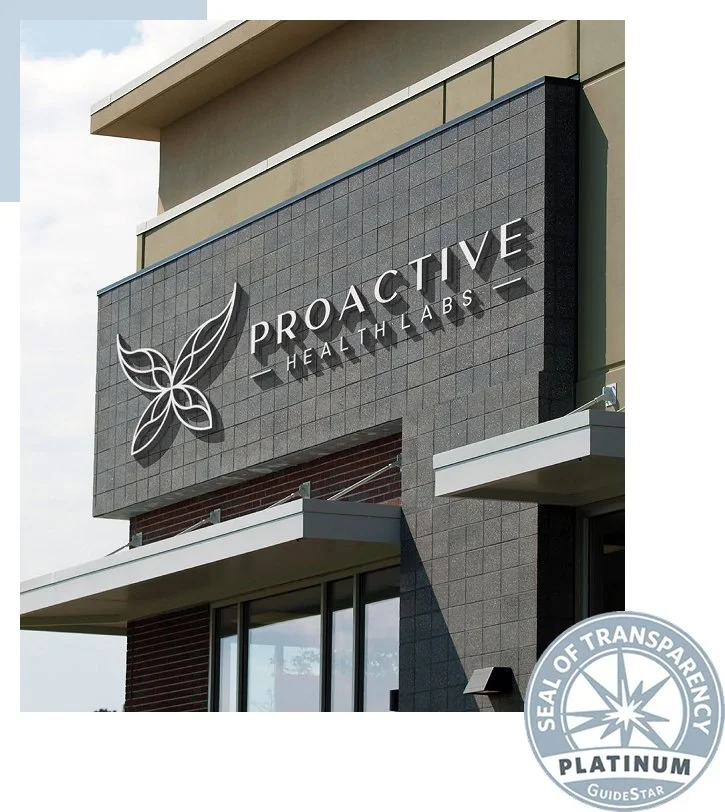Exterior of a building with a sign that reads 'Proactive Health Labs' and features a butterfly logo. There is also a 'Seal of Transparency Platinum' badge in the bottom right corner.