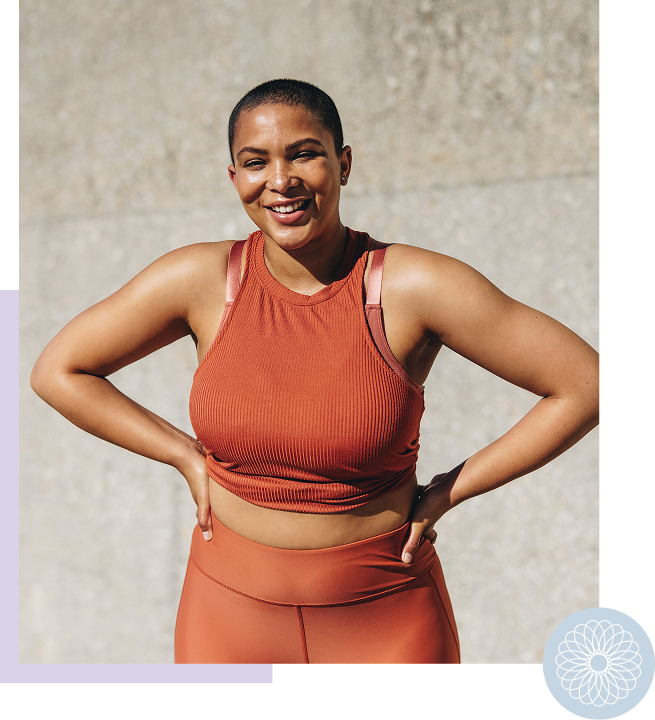 A smiling woman with short hair wearing an orange athletic tank top and matching leggings outdoors.