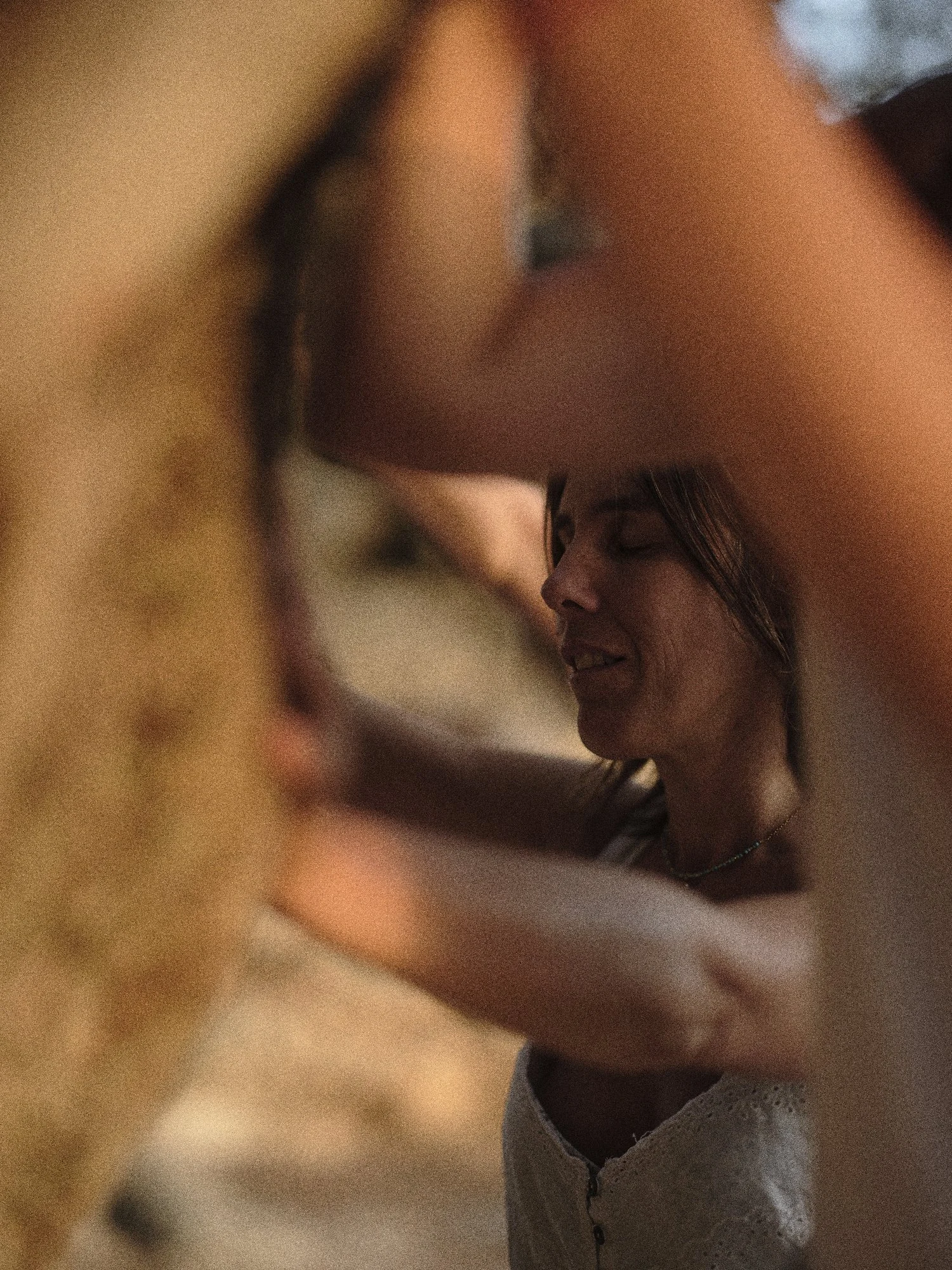 Mujer sonriendo con los ojos cerrados, rostro parcialmente visible a través de varios objetos en primer plano