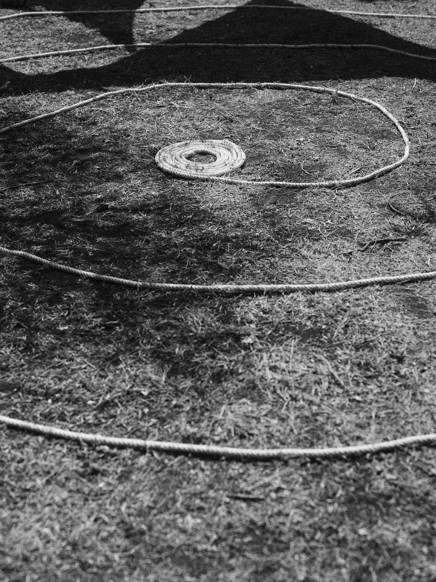 Líneas de cuerda en el suelo que forman círculos concéntricos, en un entorno al aire libre con tierra y sombra.