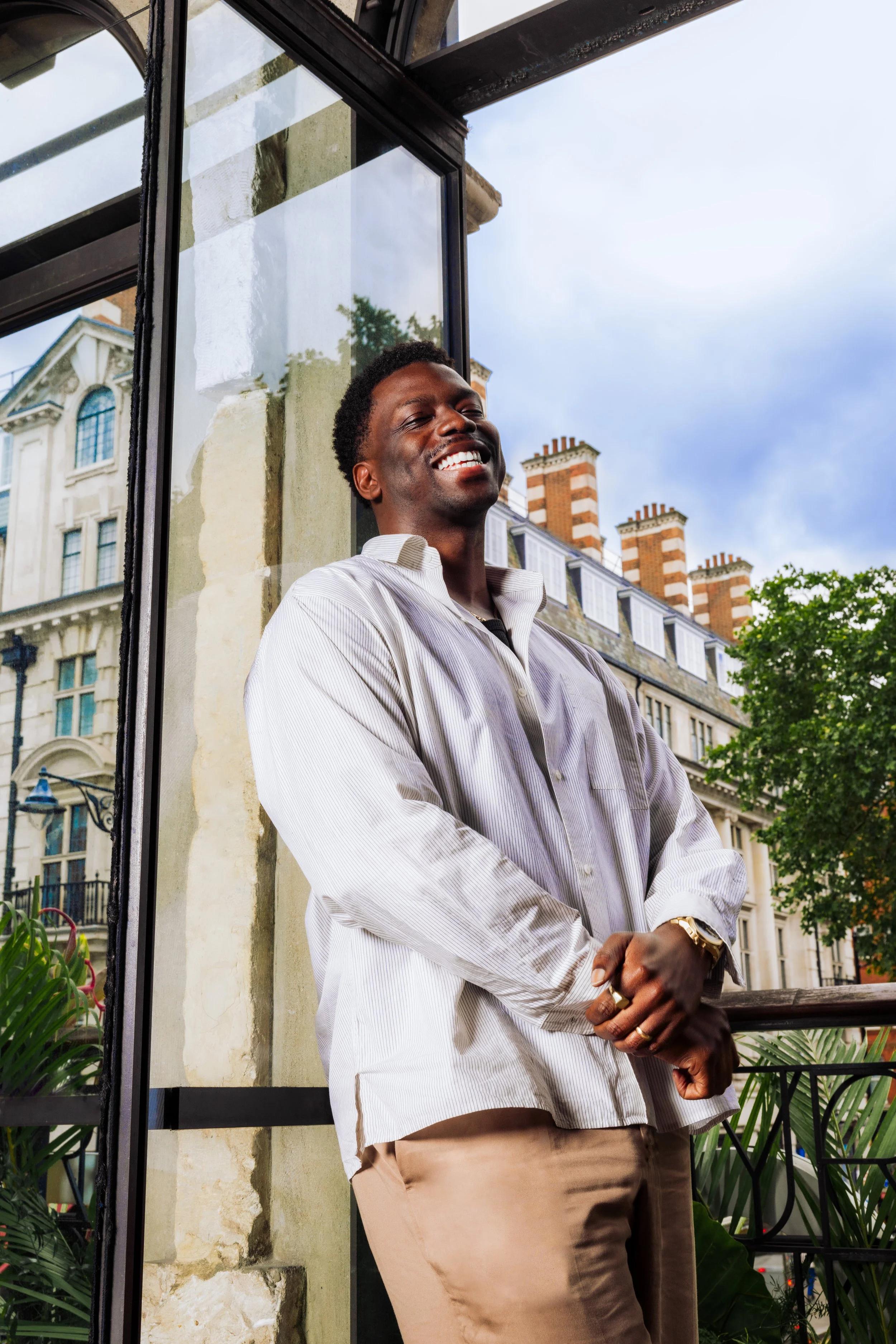 Ryan Calais-Cameron, playwright and director, leaning on a glass door of the 1st floor library at the Royal Court Theatre by London portrait photographer, Sèverine Howell-Meri