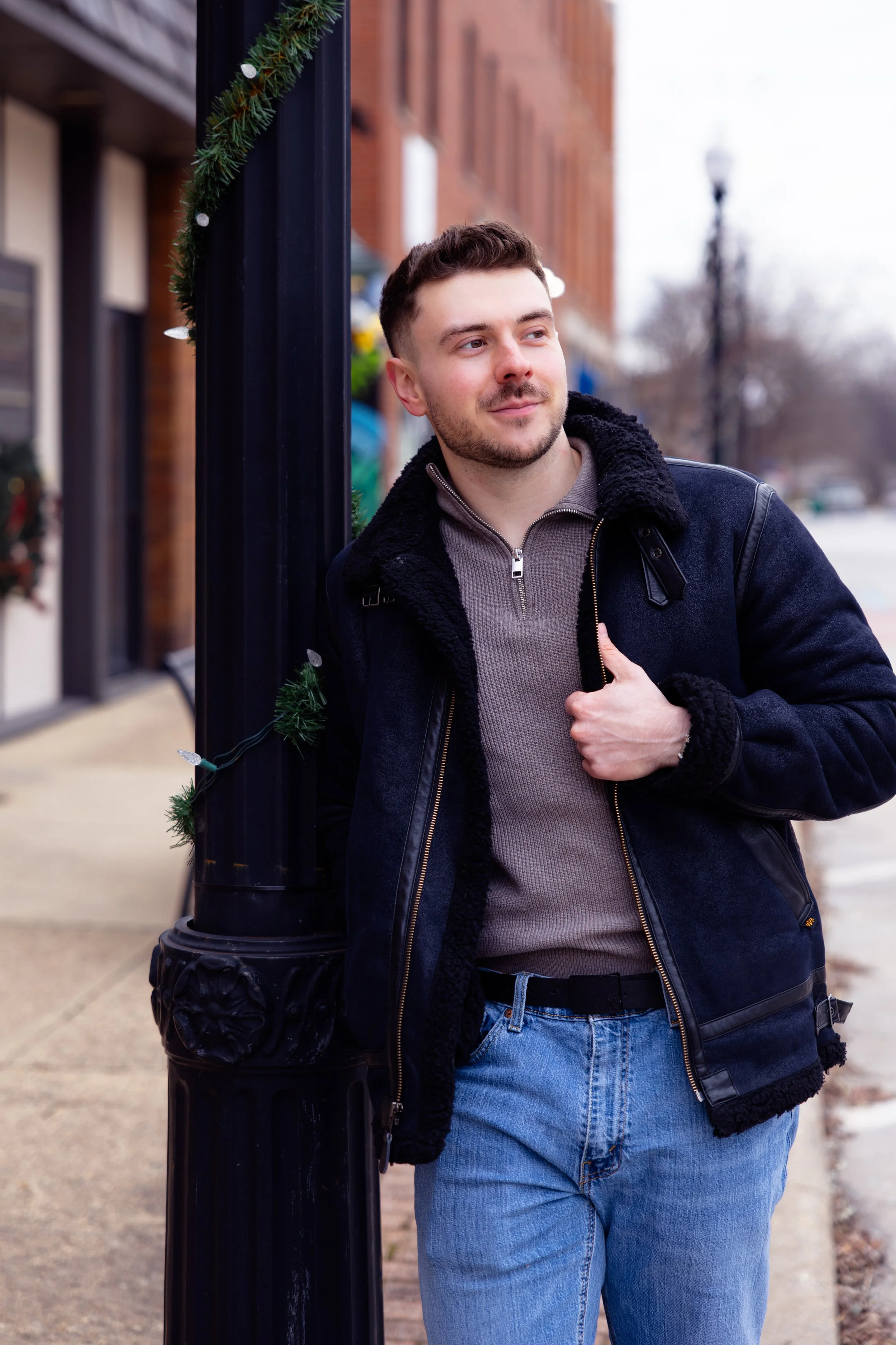 Indianapolis portrait session of a man walking leaning against a light pole in a town square in the winter