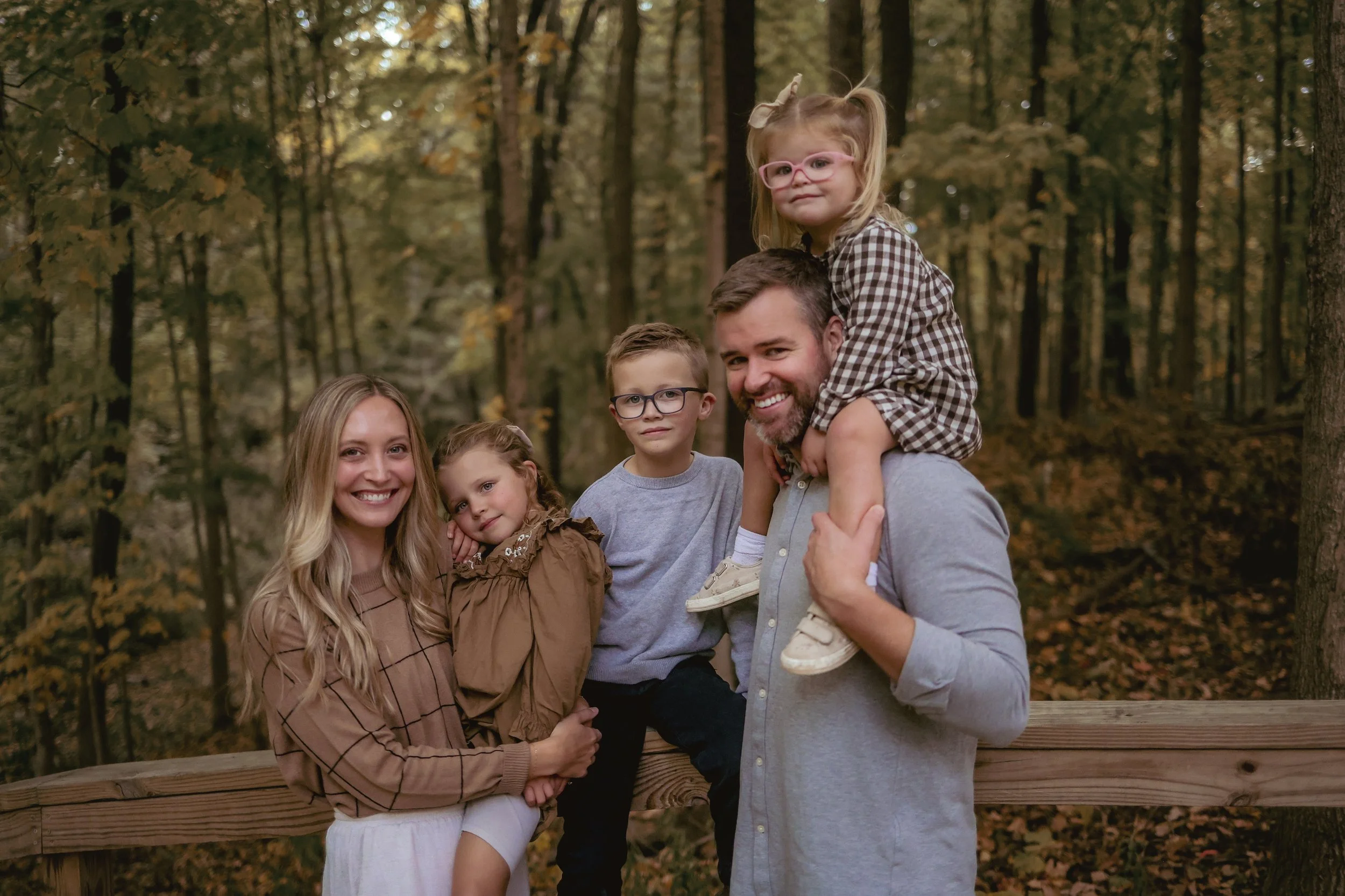 family of five posing and smiling for Indianapolis family photographer during family photo session in the fall at a park in Indianapolis