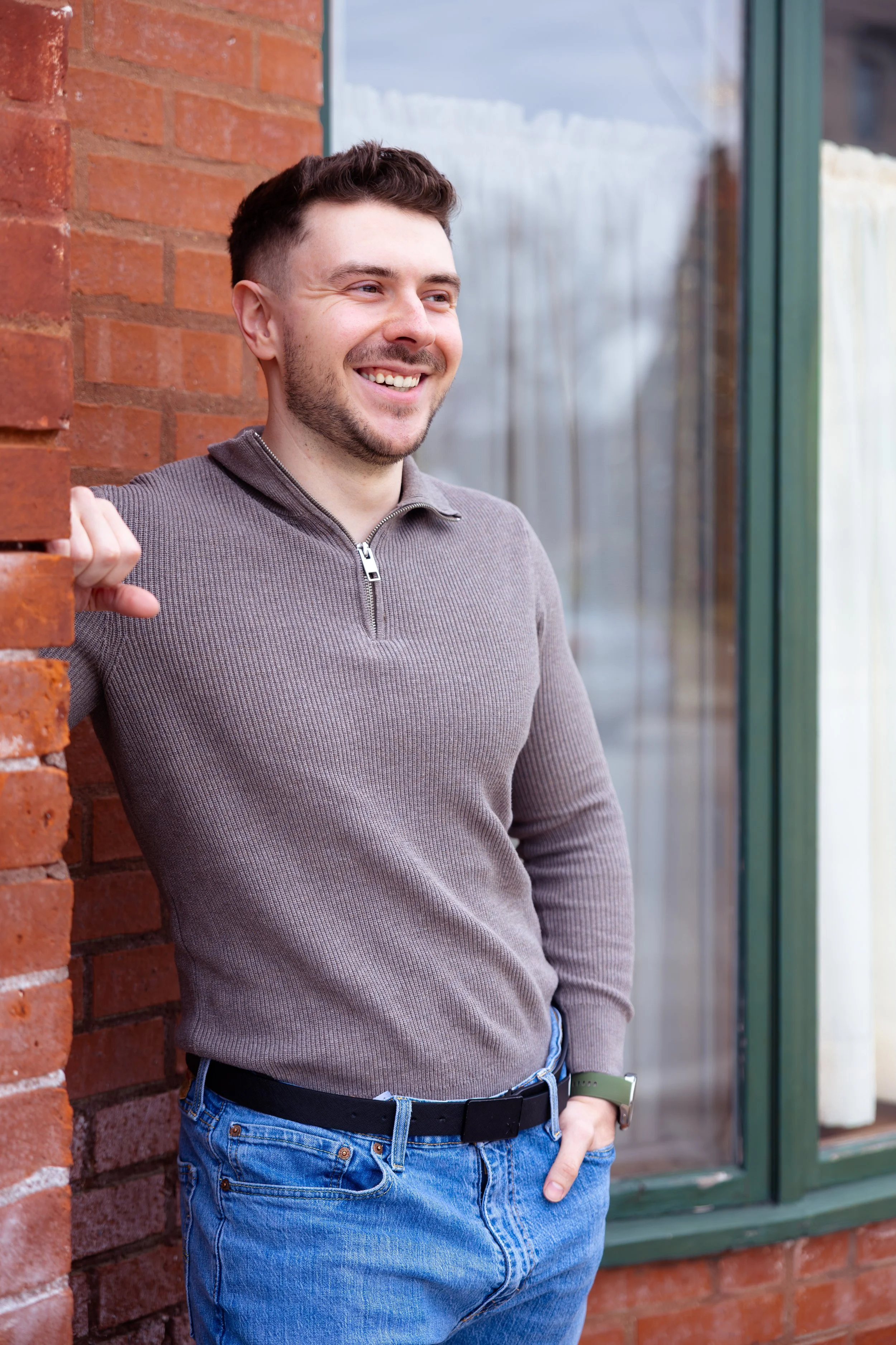 Indianapolis portrait session of a man leaning against a brick wall outdoors in winter