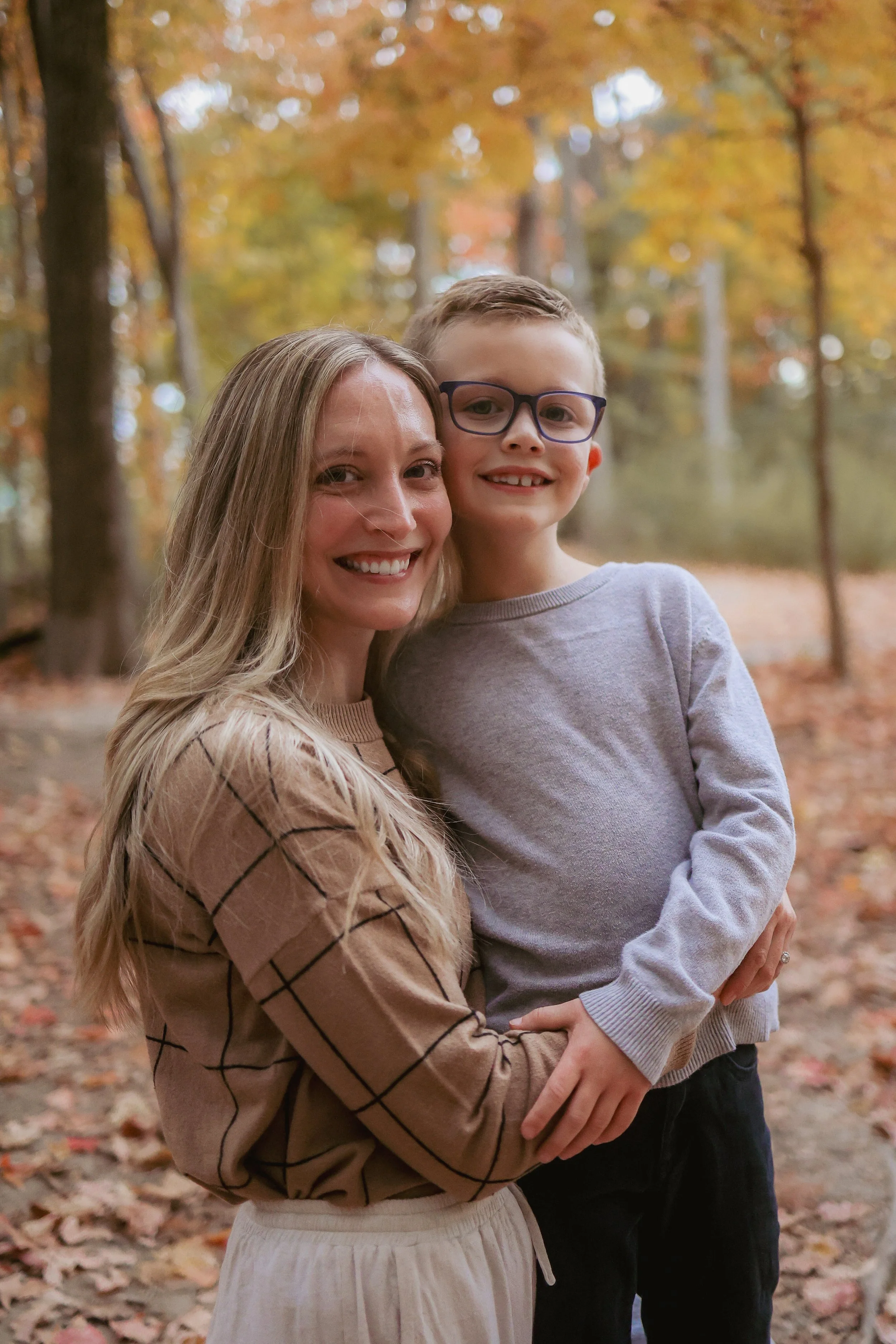 mother and young son smiling for Indianapolis family photographer in an outdoor park in the fall season for family photo session