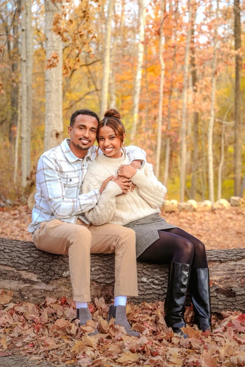 Married couple sitting together amongst the fall foliage during couples photo session in the fall at a park taken by Indianapolis couples photographer
