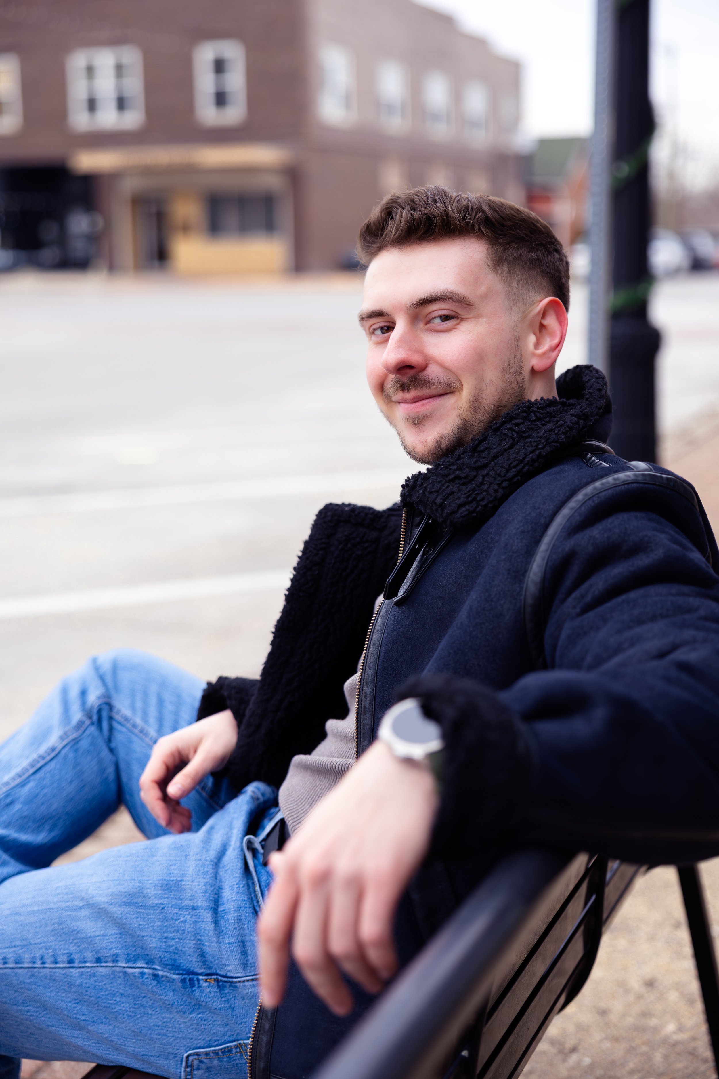 Indianapolis portrait session of a man smiling and sitting on an outdoor bench in winter