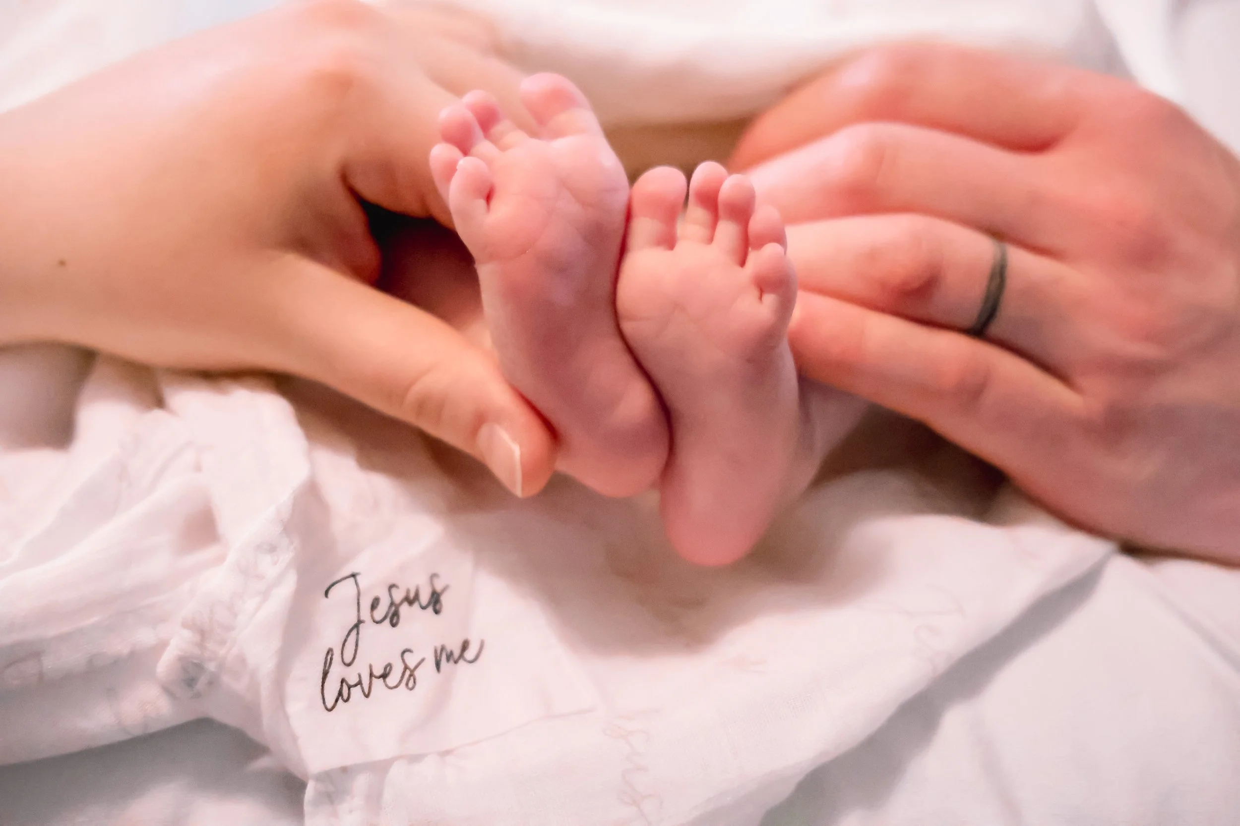 A husband and wife holding their newborn baby's feet posing for Indianapolis family photographer