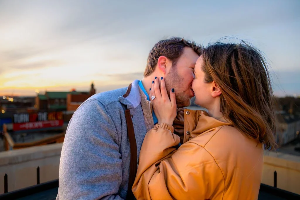 A couple is sharing a kiss on a rooftop during sunset after proposal in downtown Indianapolis
