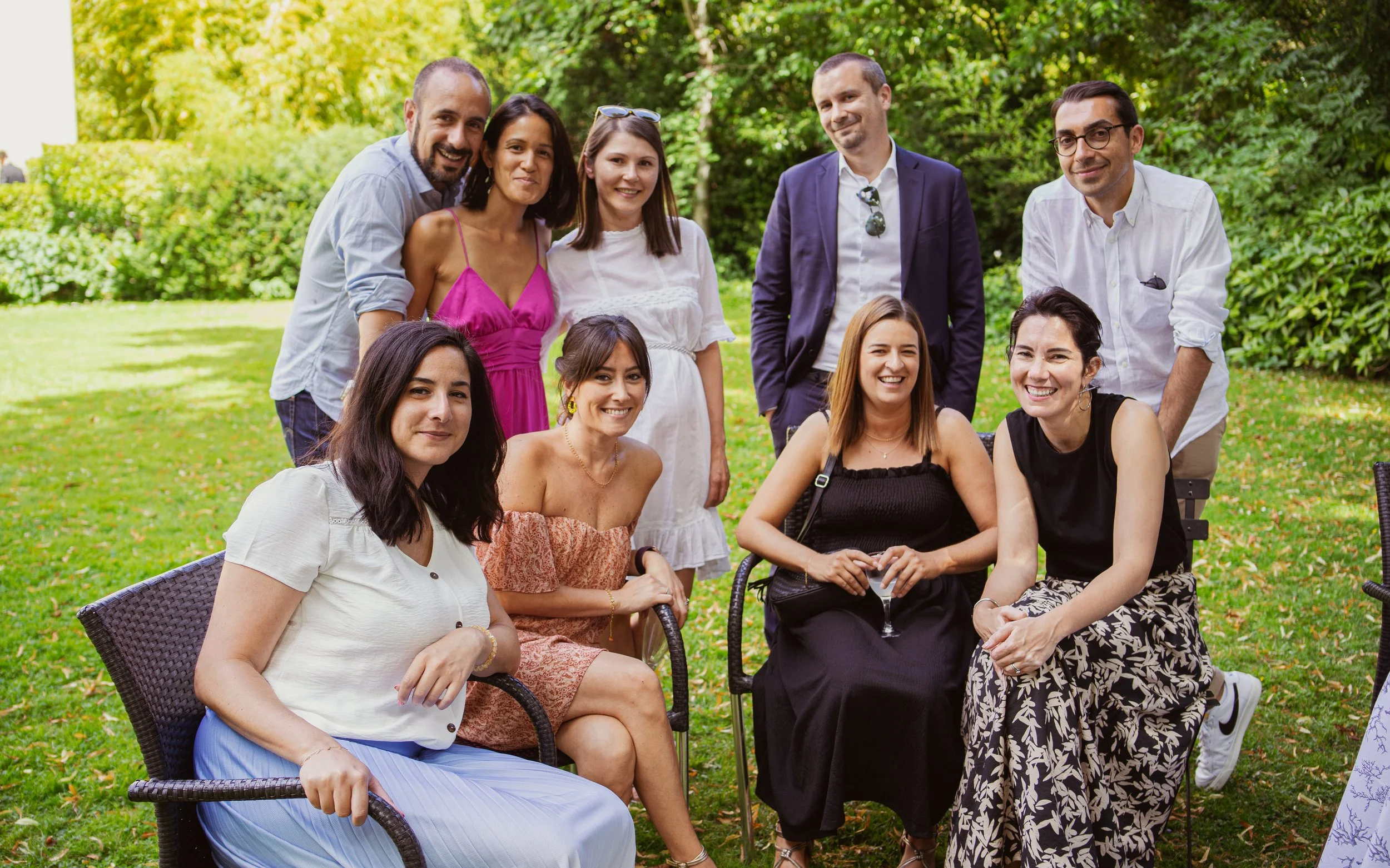 Groupe de personnes souriantes posant dans un jardin lors d'une réunion ou d'une fête en plein air.