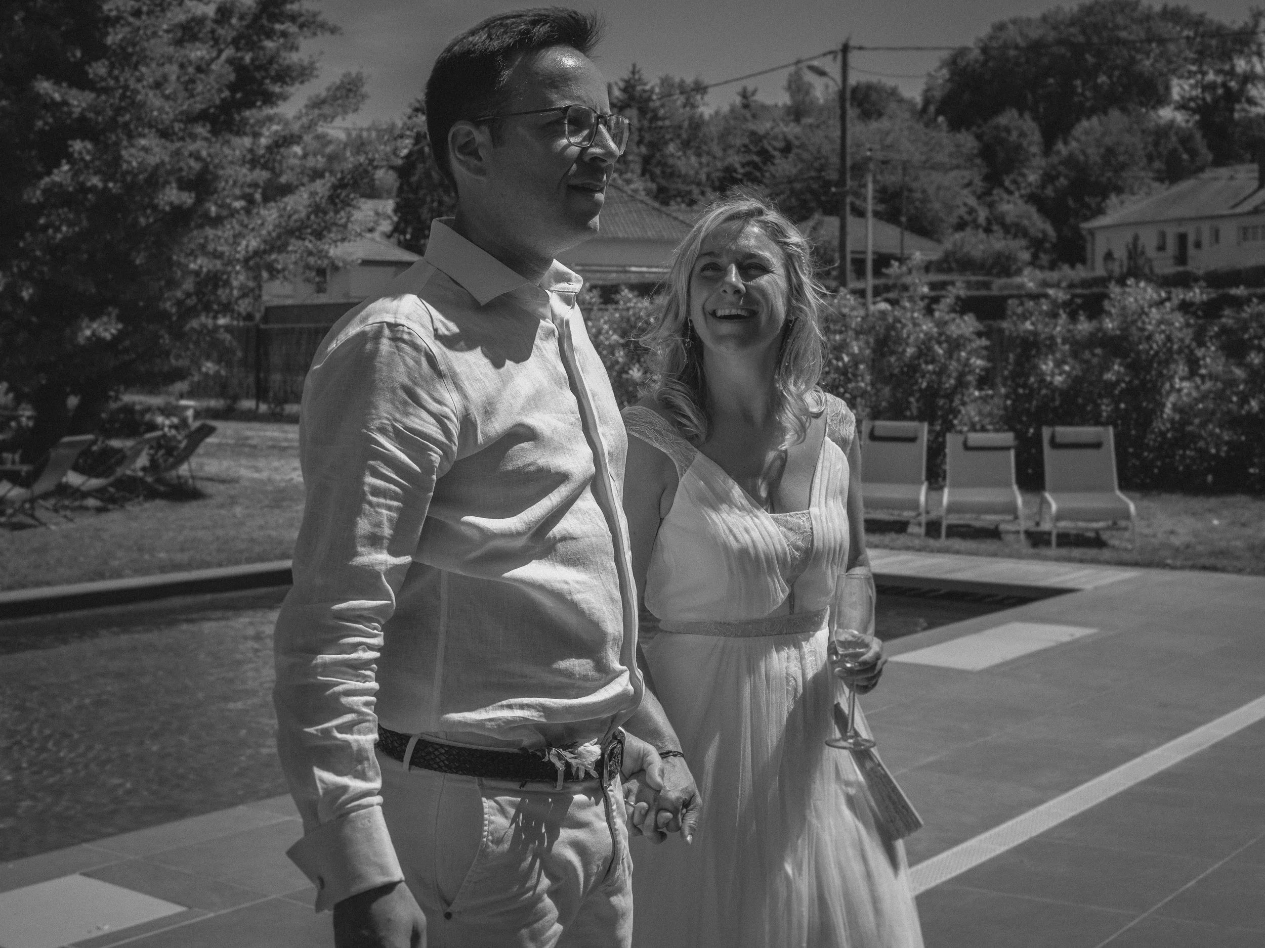 Deux personnes souriantes, un homme et une femme, tenant un verre de champagne, lors d'un événement extérieur par une belle journée