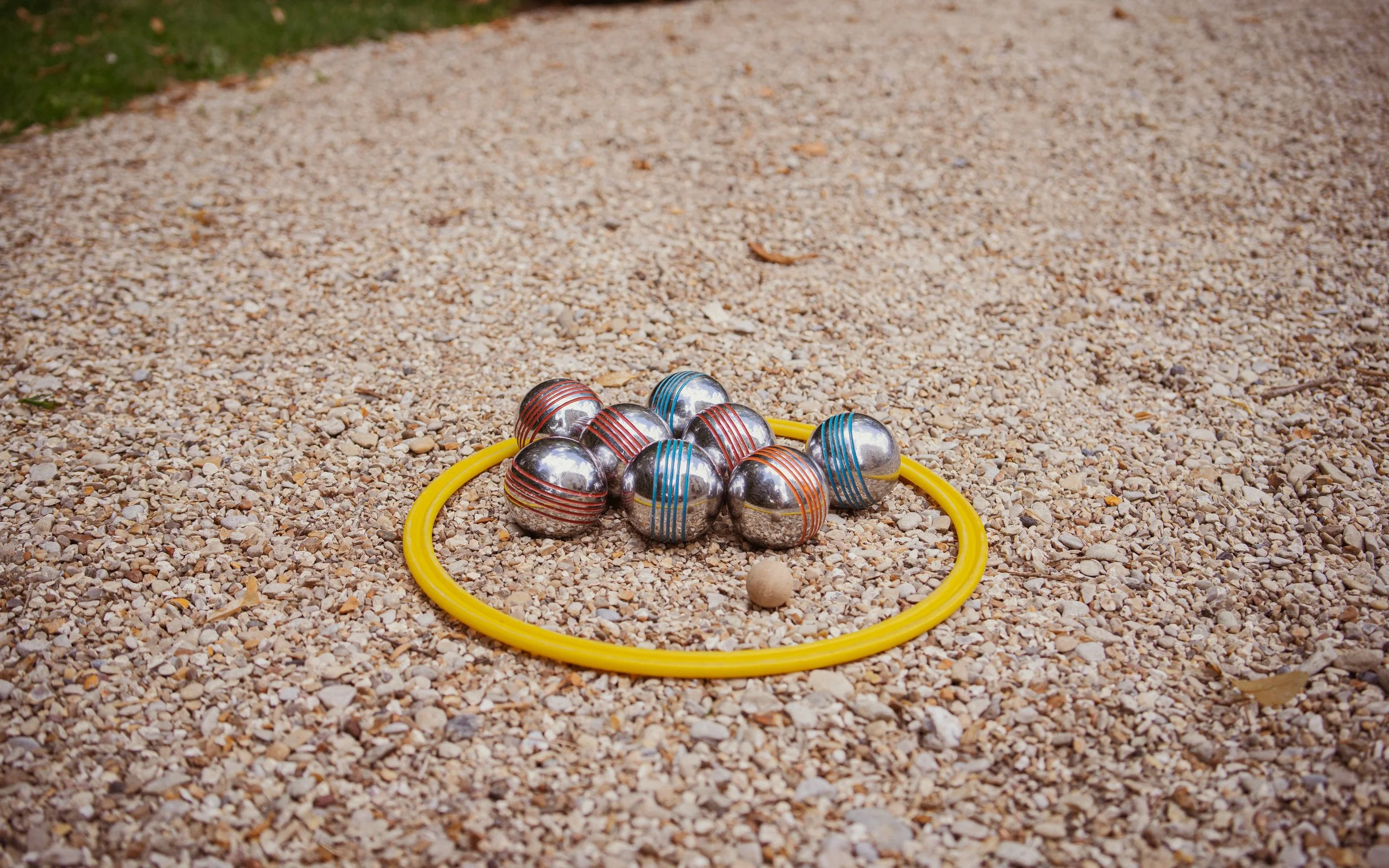 Un jeu de quilles en métal avec un anneau jaune et une balle en bois placé sur un sol en gravier.
