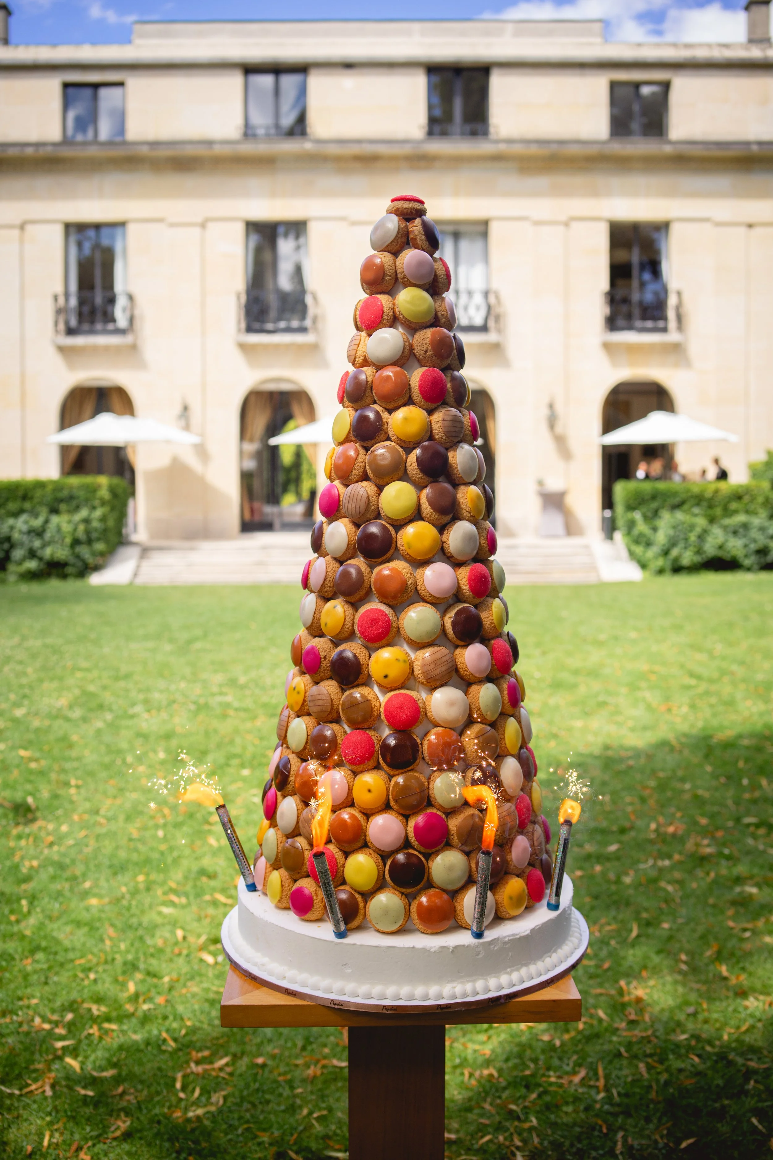Gâteau en forme de sapin de macarons de différentes couleurs, décoré avec des feux d'artifice