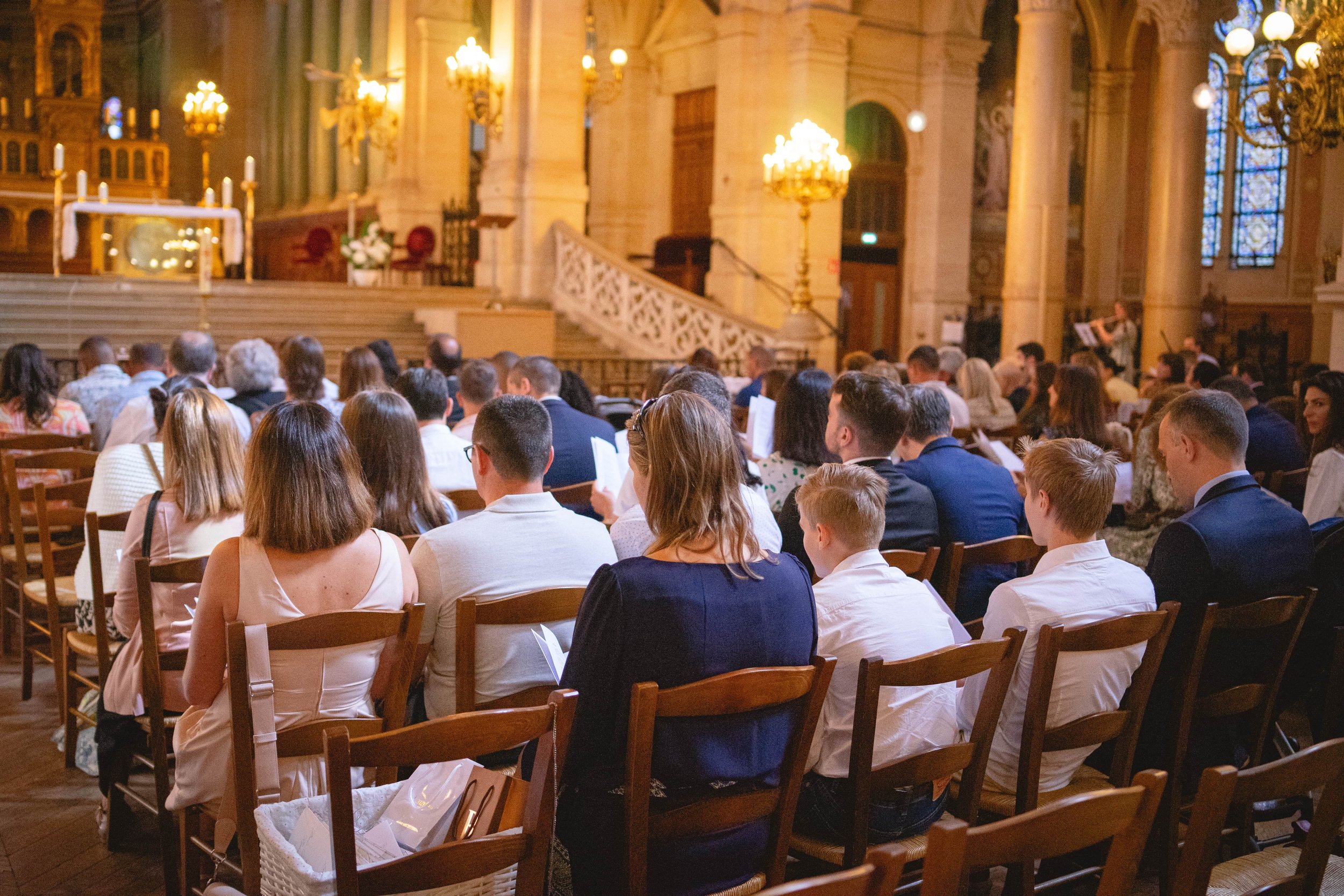 Un rassemblement de personnes assises dans une église ou une cathédrale, probablement pour une cérémonie ou un service religieux.