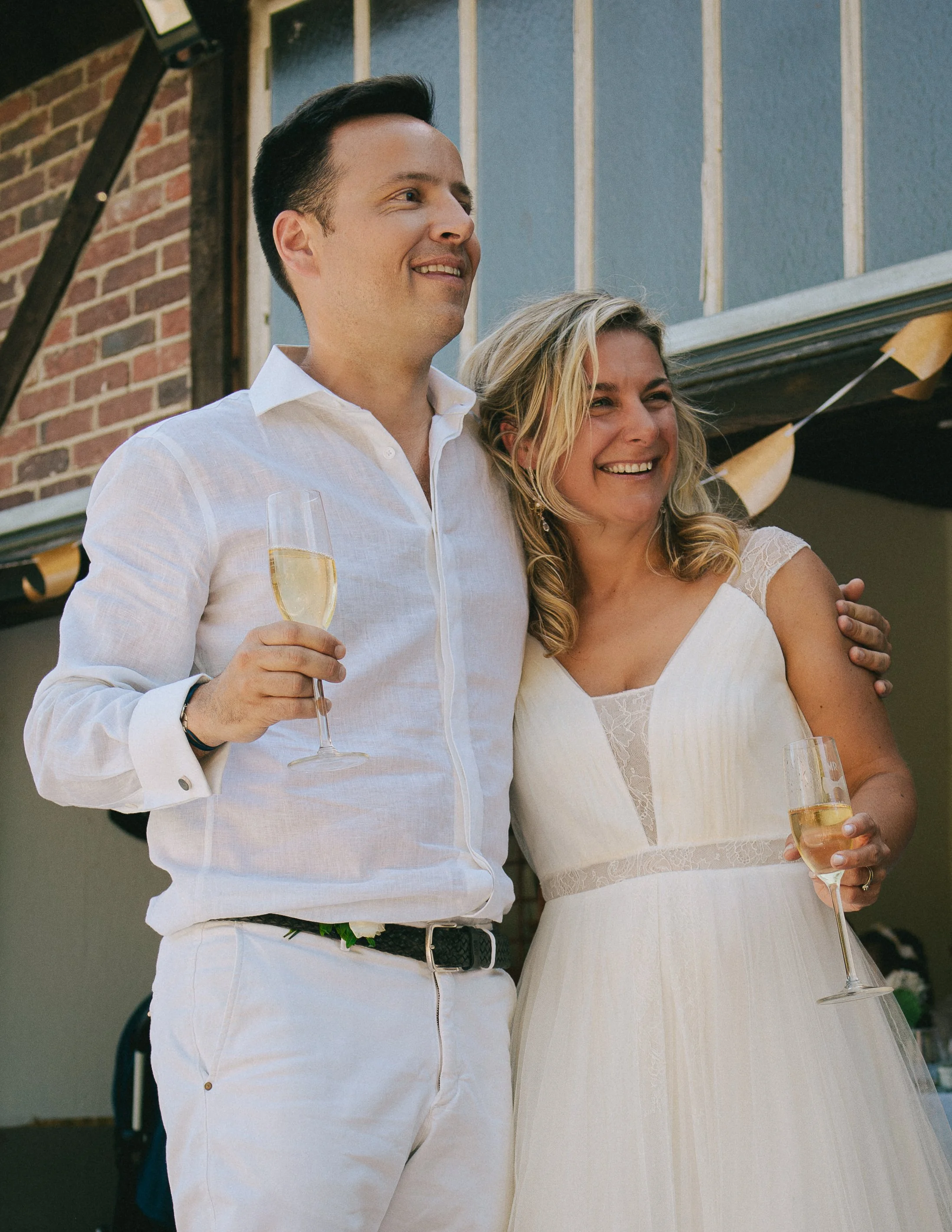 Un couple souriant fête avec des coupes de champagne lors d'un mariage en extérieur.